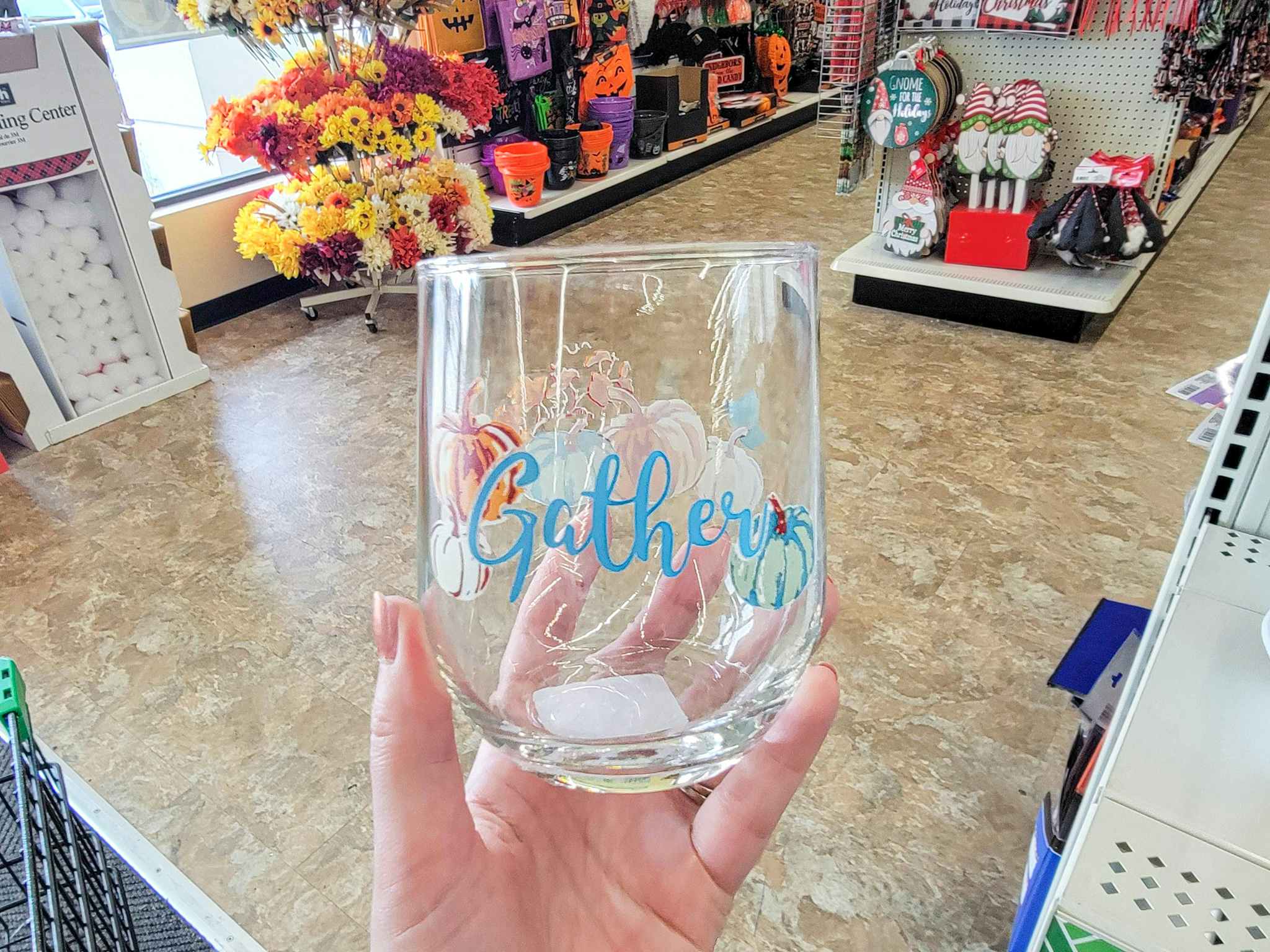 hand holding a stemless wine glass that says gather in blue