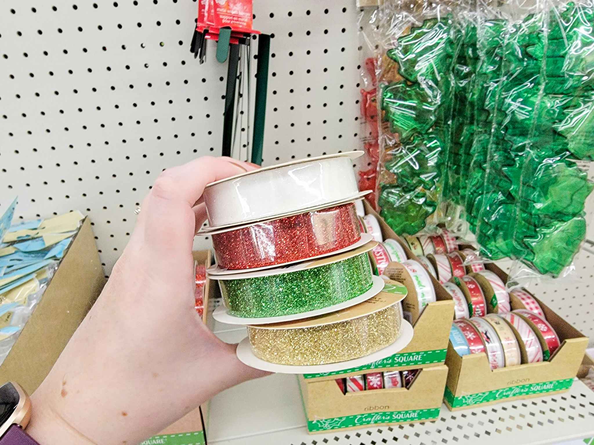 hand holding white, red, green, and gold sparkle ribbon