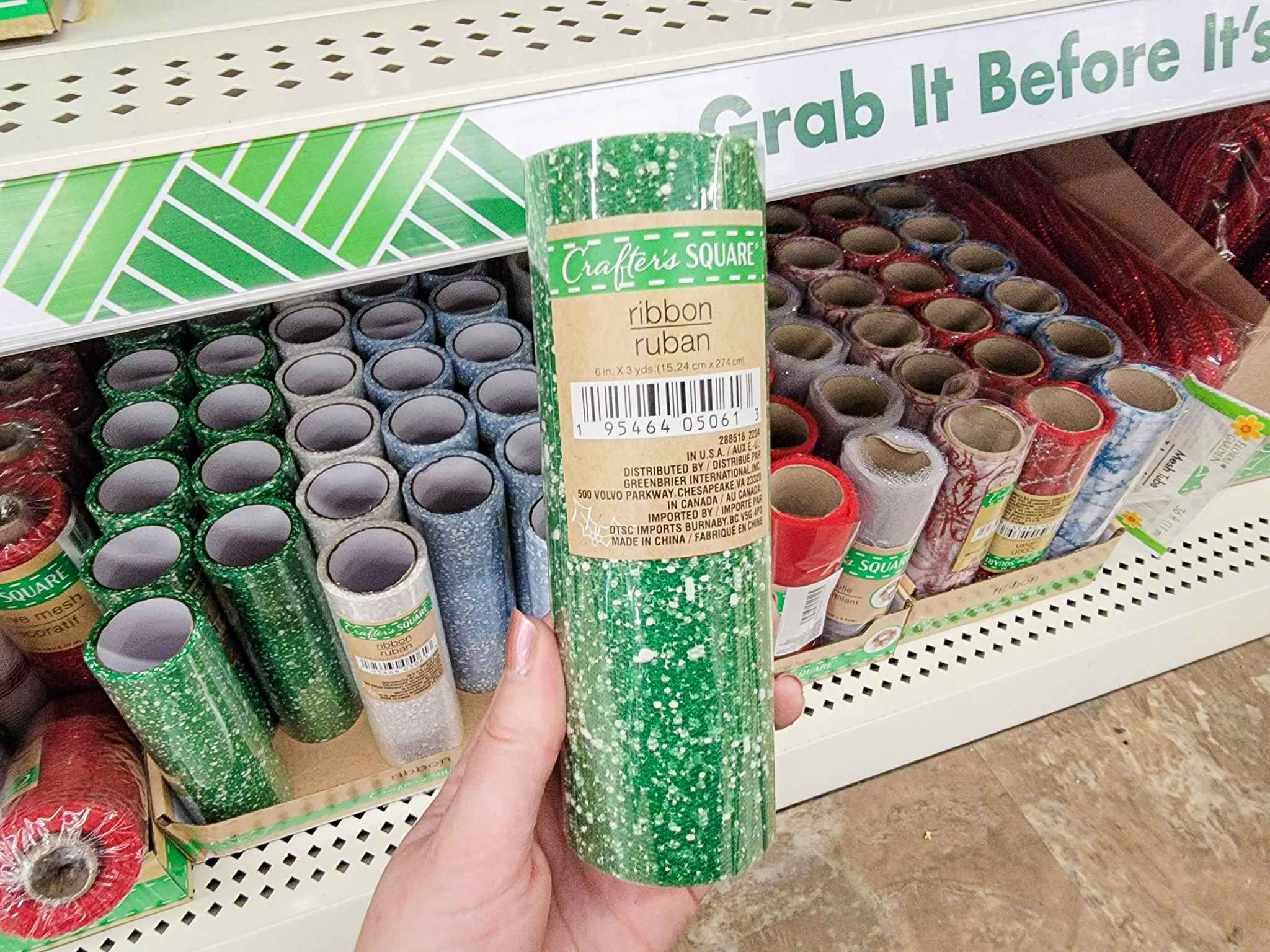 hand holding a roll of green with white speckle craft ribbon