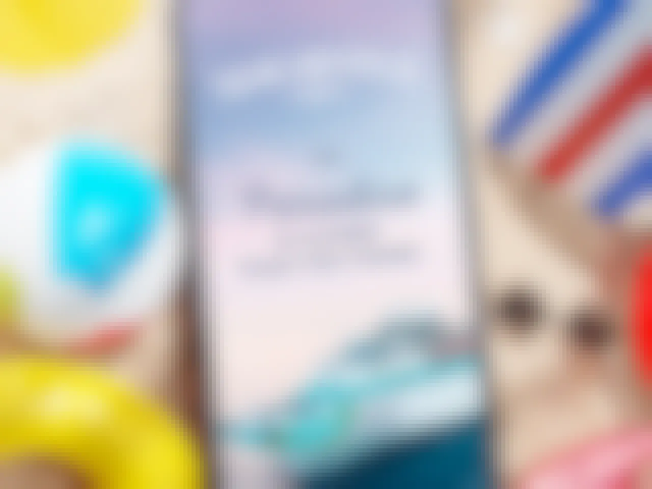 A phone sitting on sand with beach accessories around it, the screen displaying an image of the Margaritaville at Sea cruise ship and the words "Paradise is closer than you think
