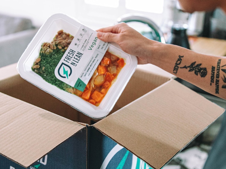 A person pulling a pre-made meal from a box