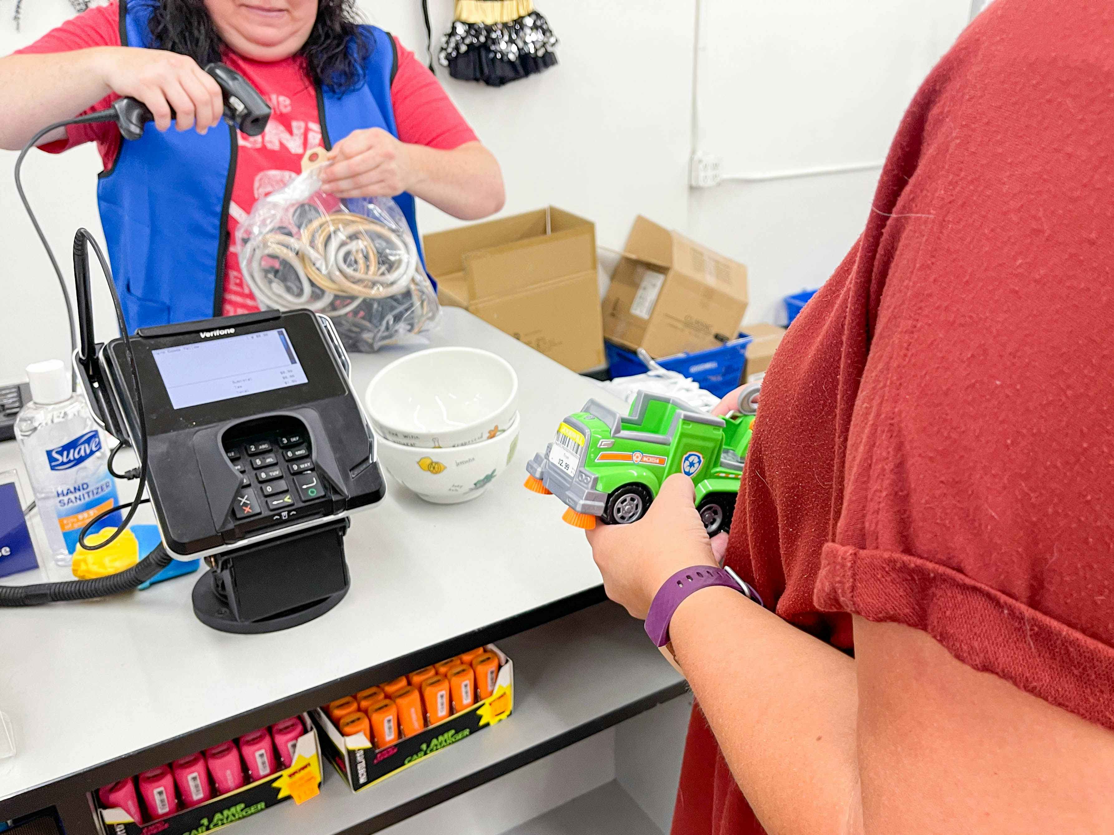 a person standing at goodwill checkout while an employee scans their items