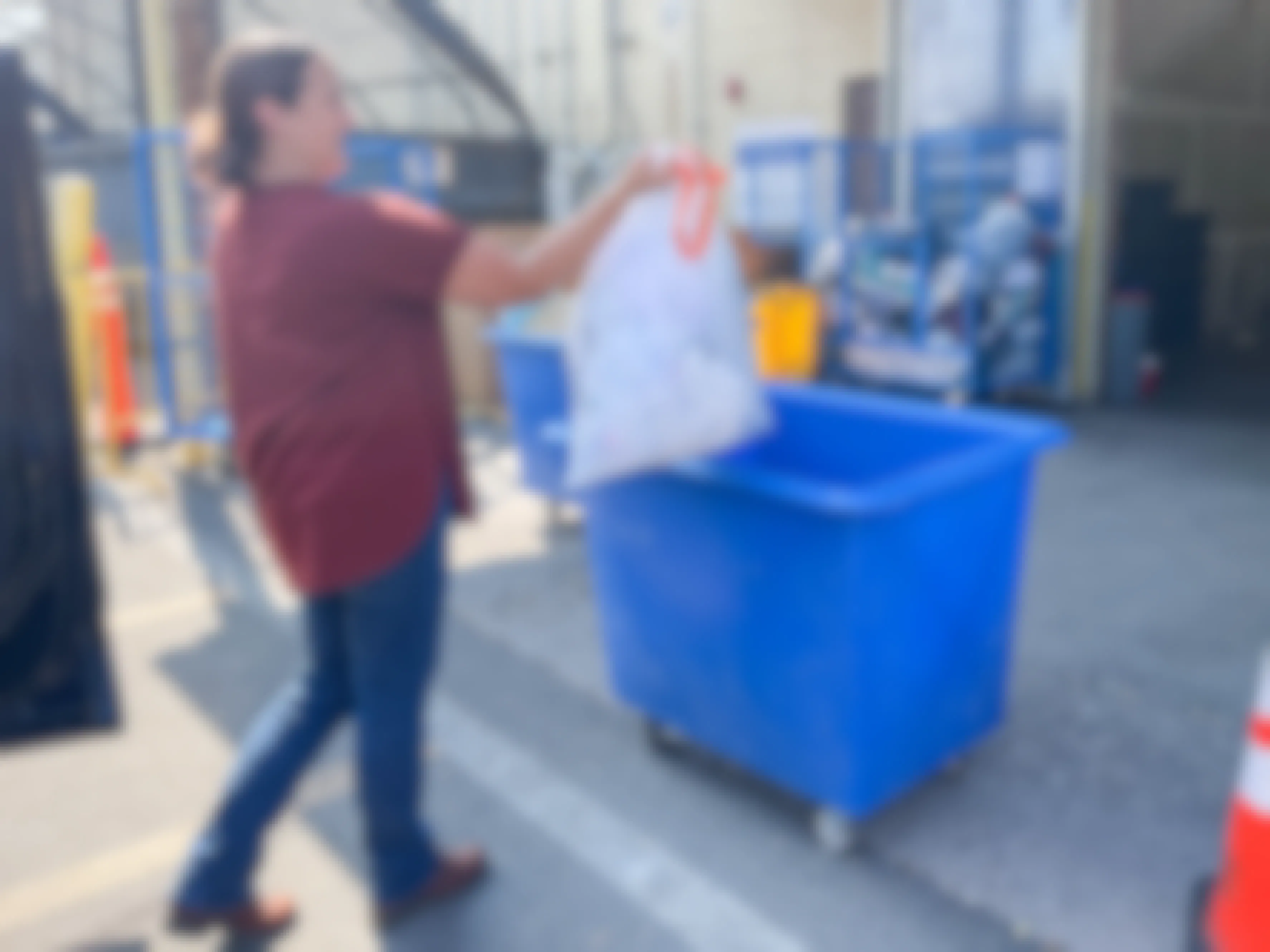 a woman putting a bag of clothes in a donation bins 