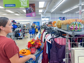 a woman putting stuff in a shopping cart filled with fall and halloween decor