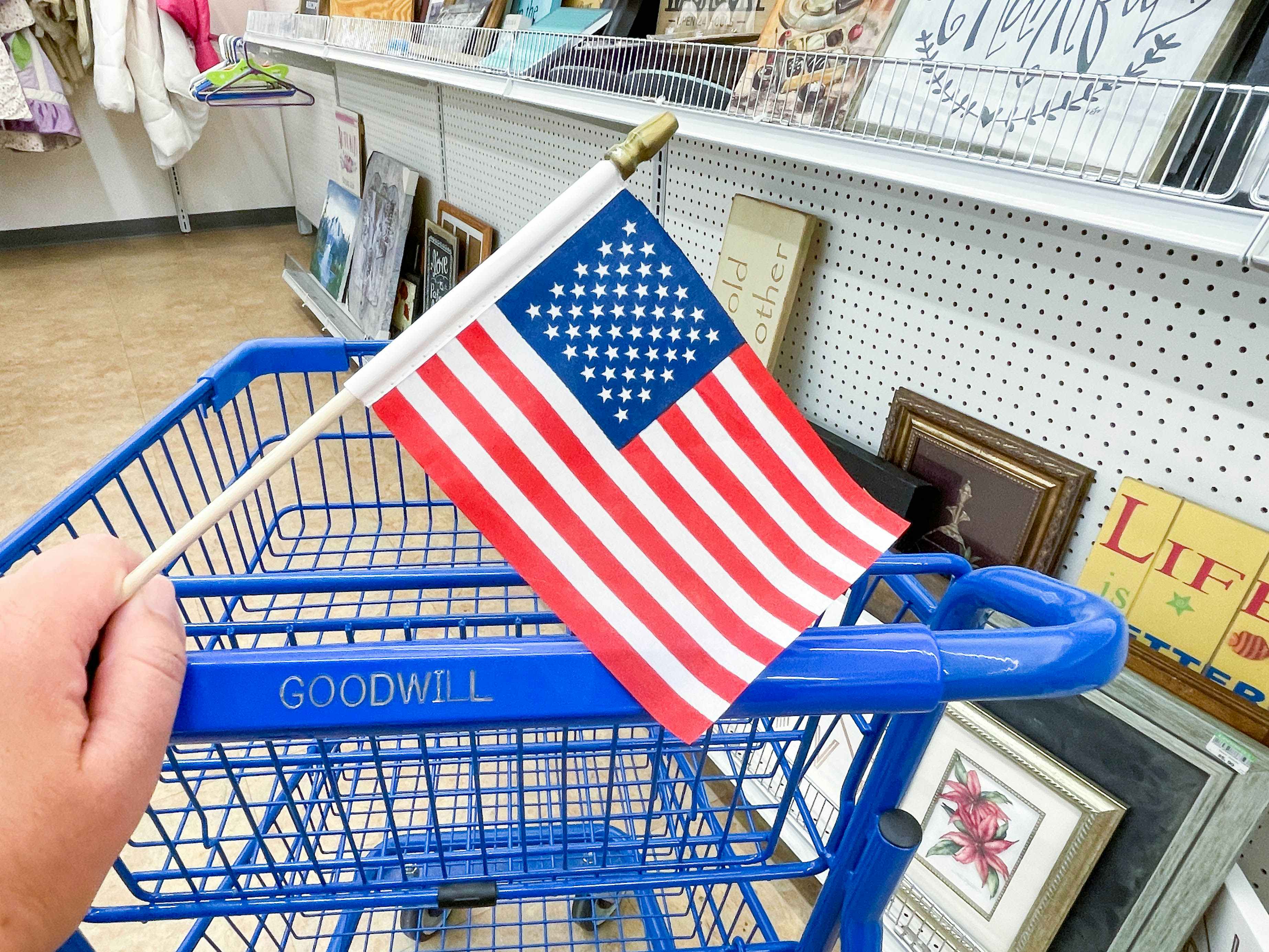 an american flag being held in front of goodwill cart 