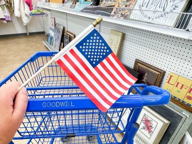 an american flag being held in front of goodwill cart 