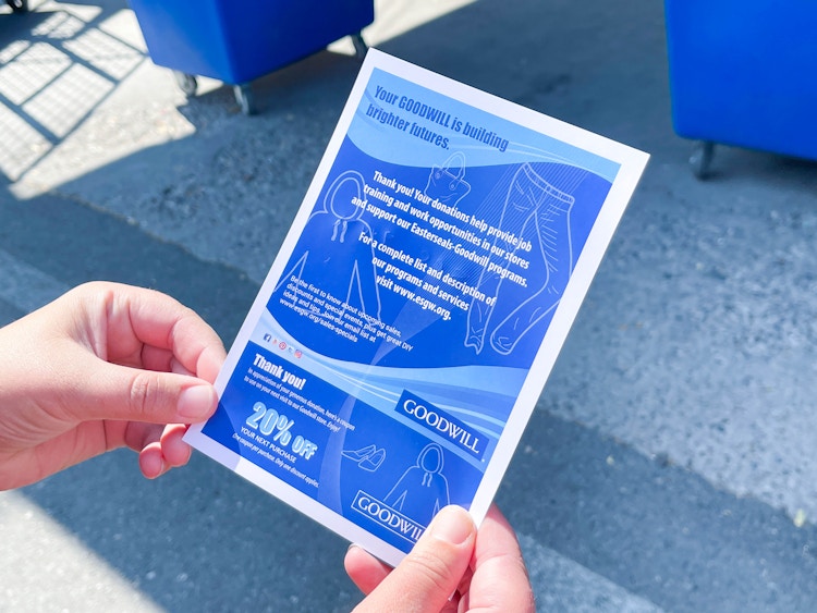 a person holding goodwill donation coupon and tax receipt