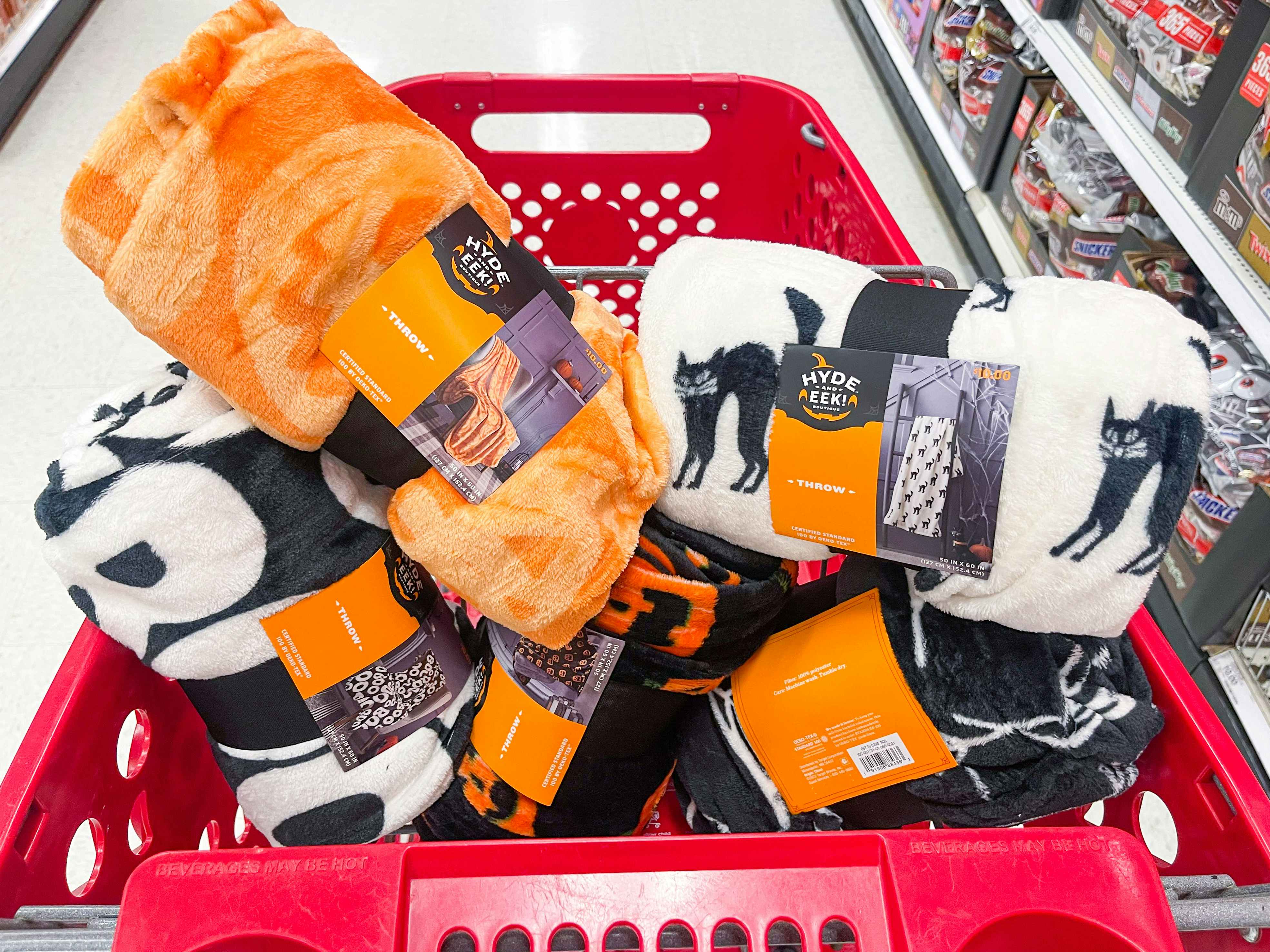 A variety of plush Halloween throw blankets sitting in a Target shopping cart.