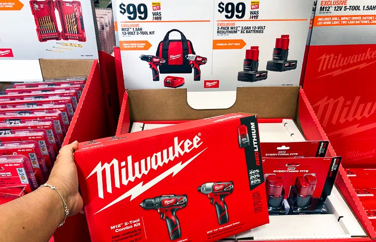 a woman's hand holding a milwaukee tool set in front of a sale display at Home Depot