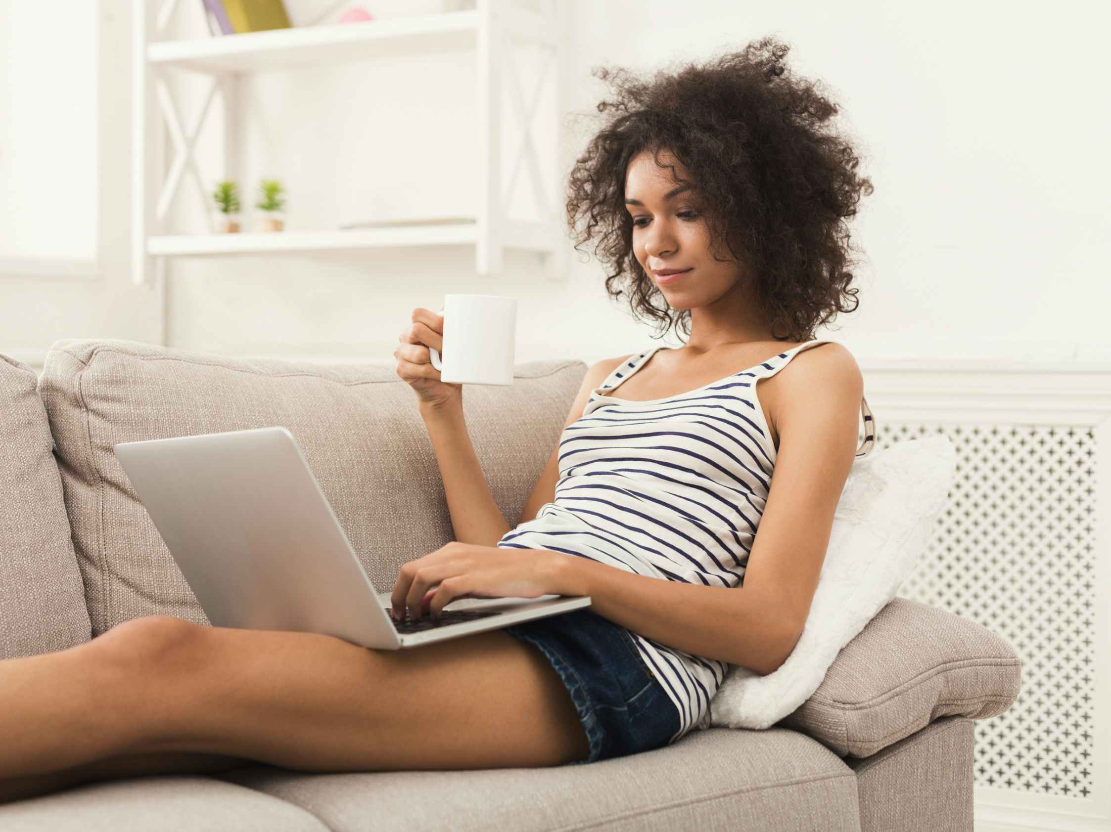 A woman sitting on a couch, using a laptop.
