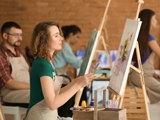 Adults sitting in front of easels in a painting class.
