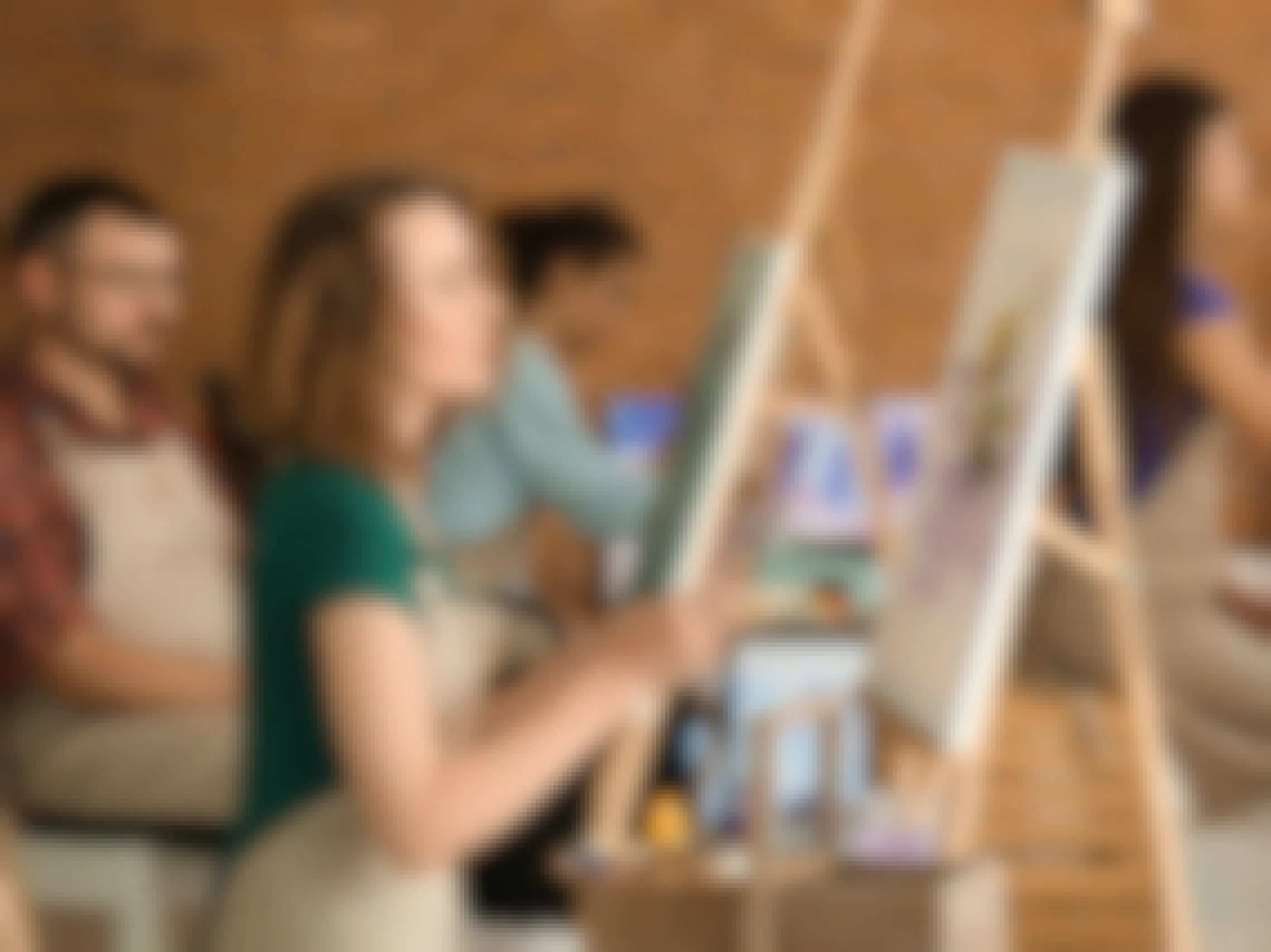 Adults sitting in front of easels in a painting class.