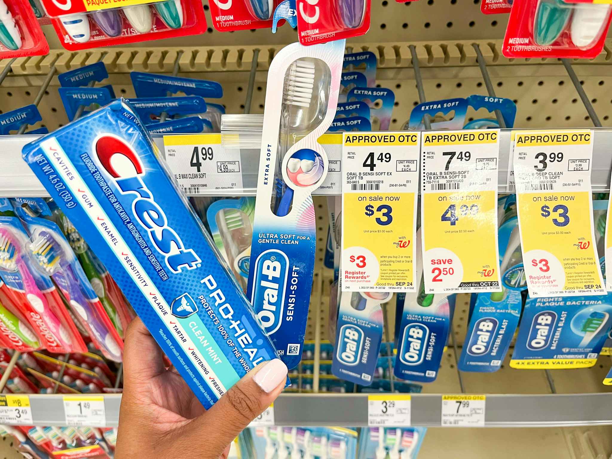 hand holding crest and oral b next to sale signage