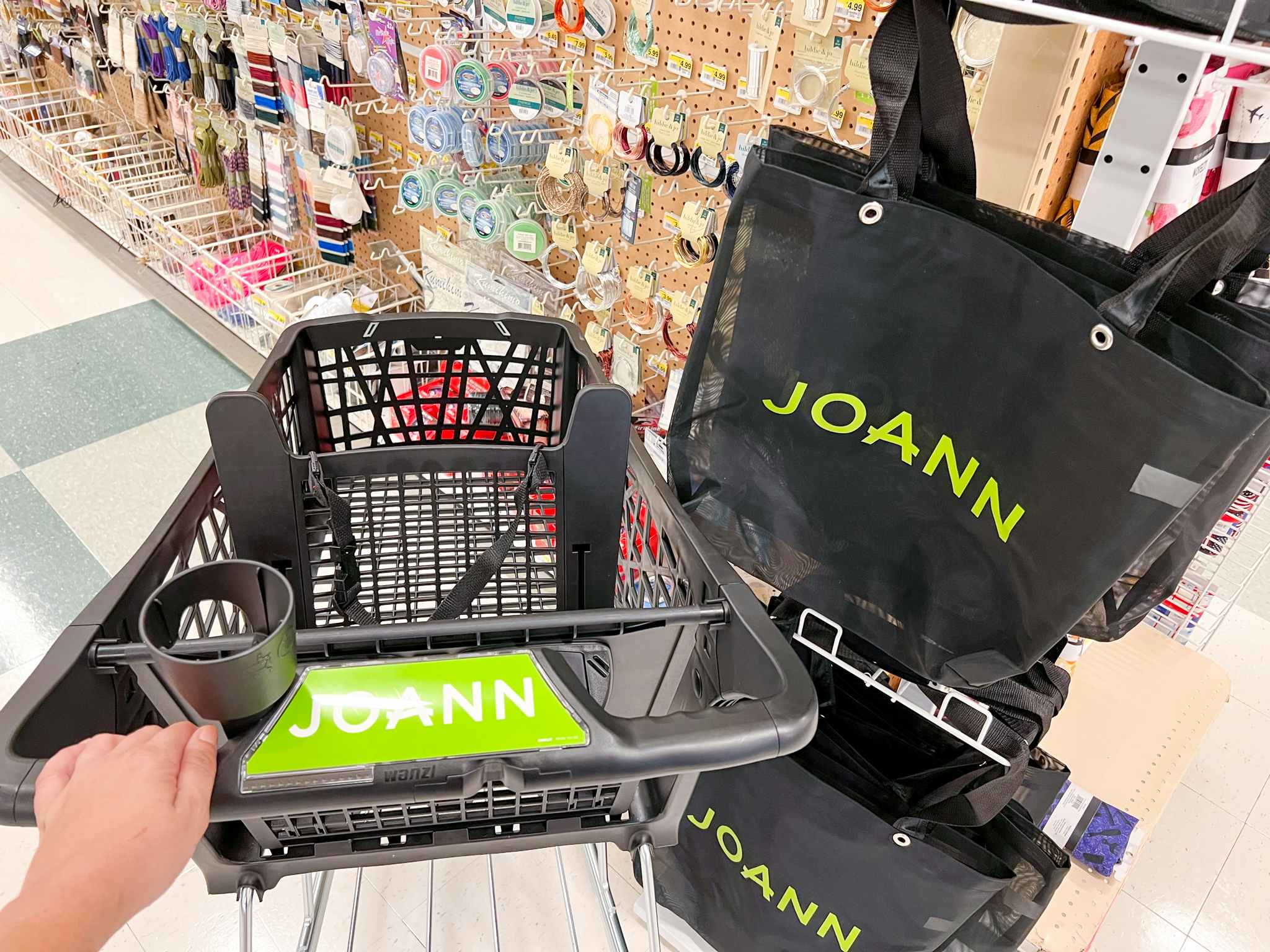 A hand pushing a Joann Fabric shopping cart