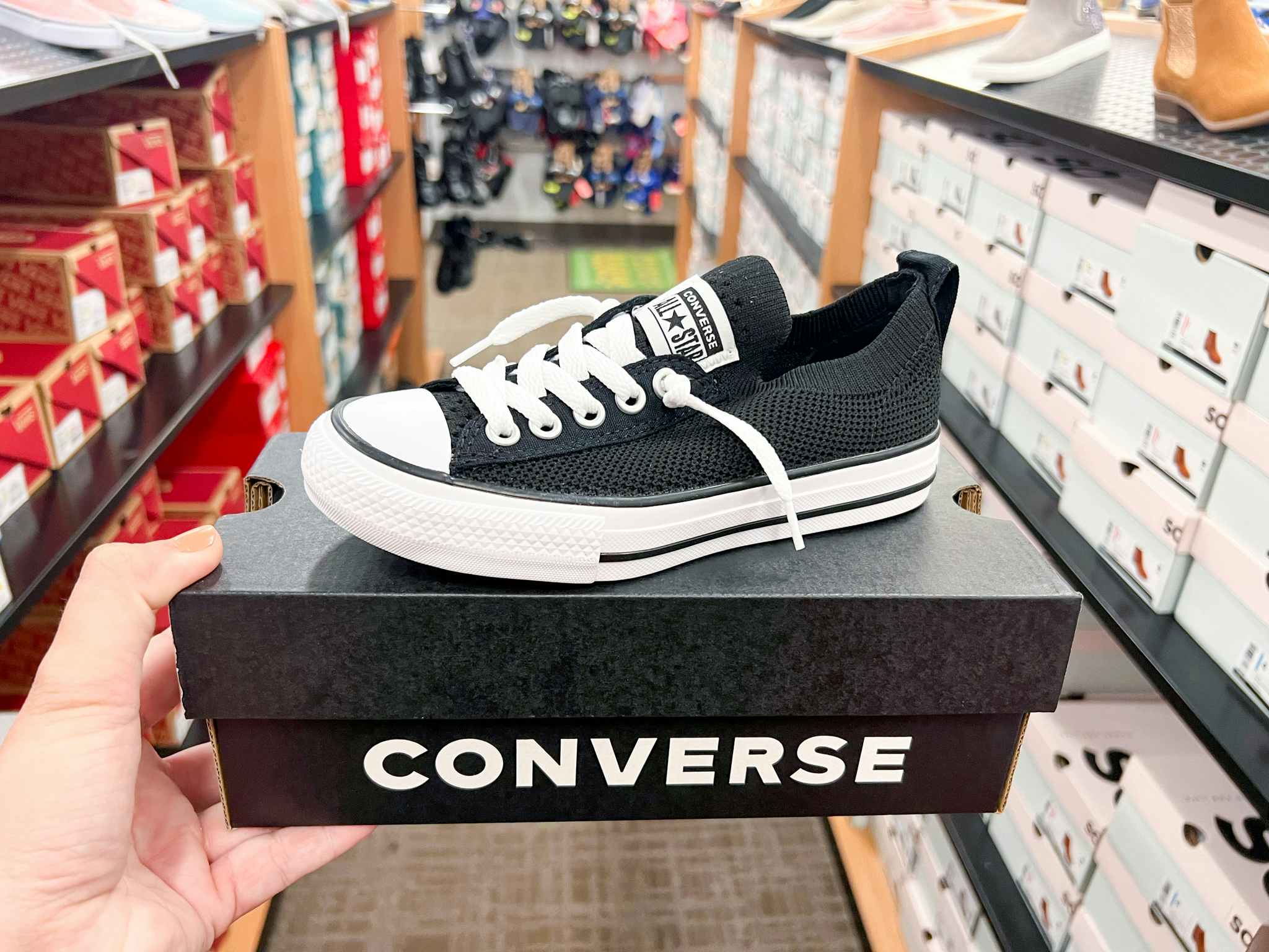 someone holding converse shoes