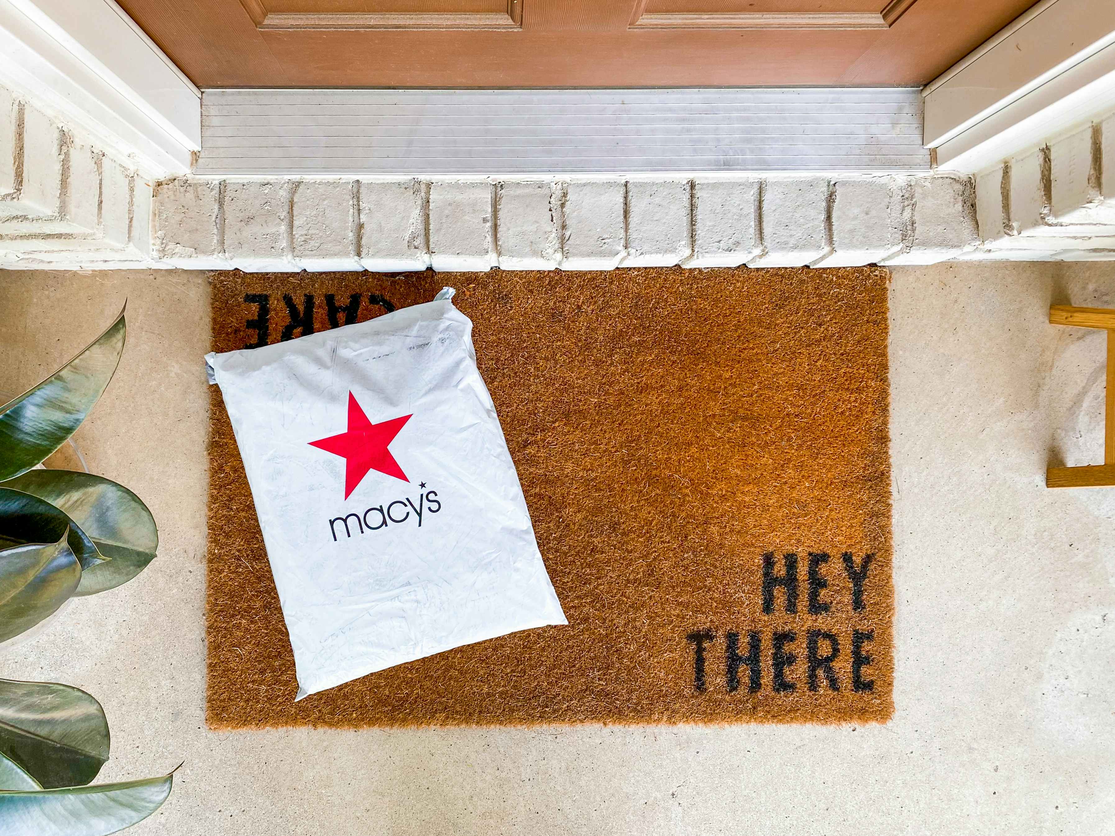 A Macy's online order package on a mat outside a front door.