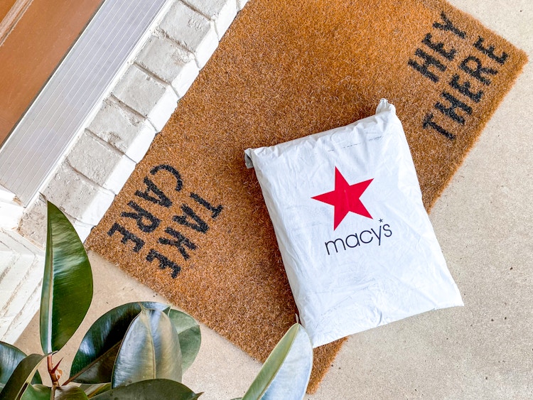 A Macy's online order package on a mat outside a front door.