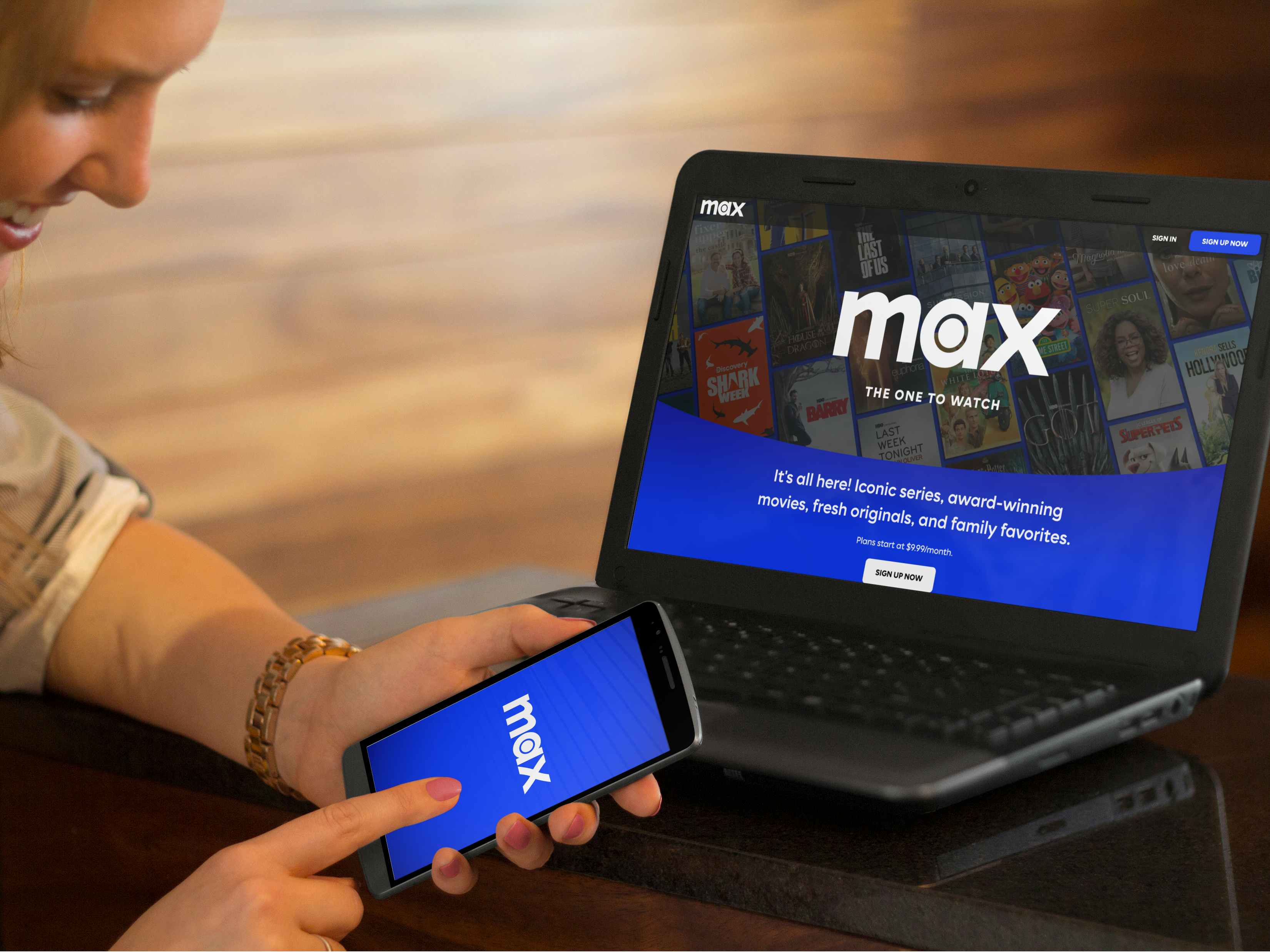 Mockup of a woman looking at the Max streaming service on a phone and laptop simultaneously