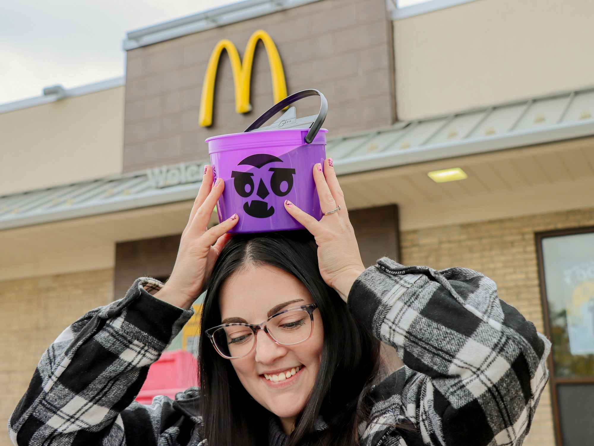 a person holding up a mcdonalds bucket outside of mcdonalds