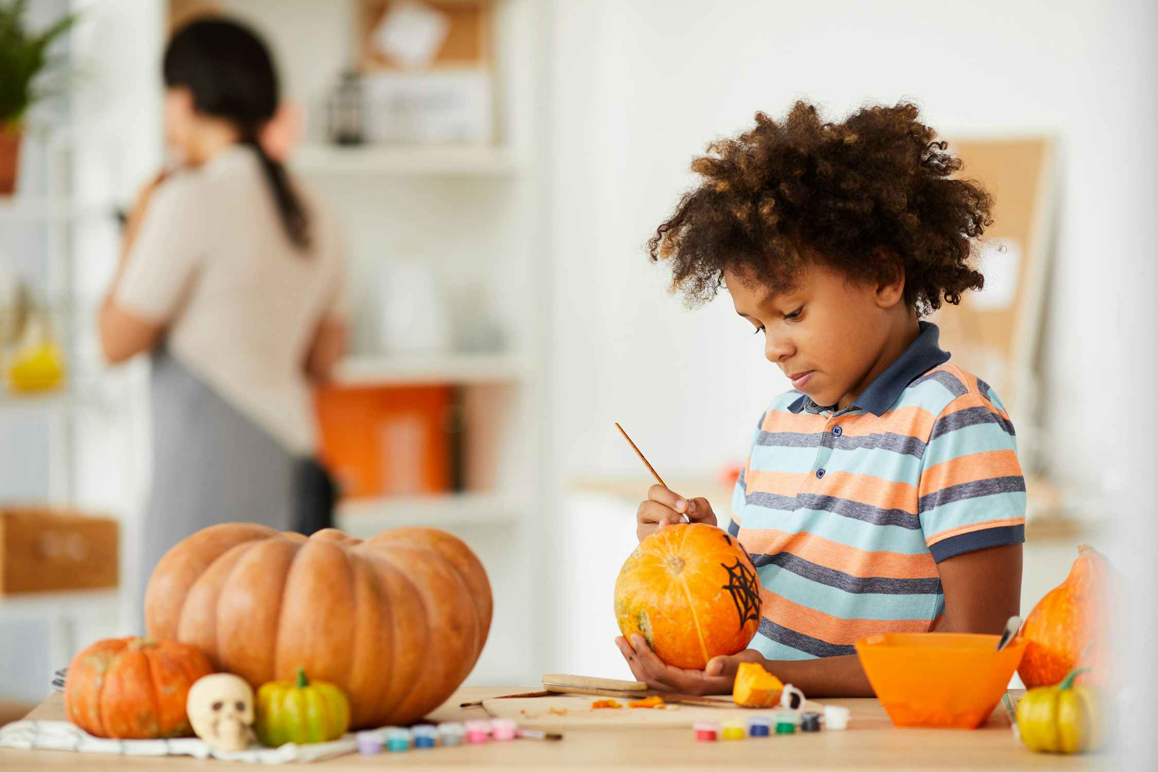 young boy painting pumpkins at home
