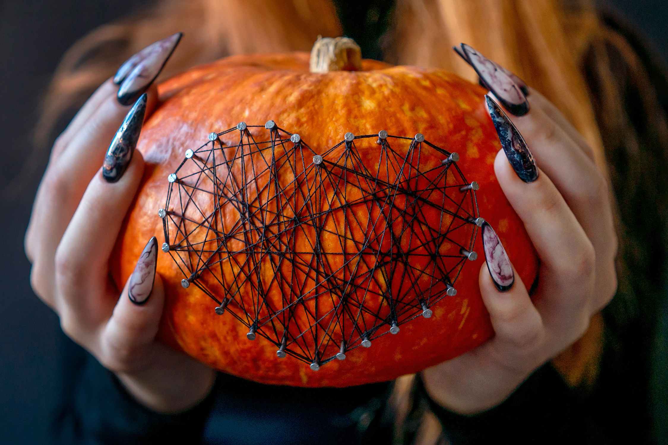 woman holding small pumpkin with heart-shaped nailhead trim