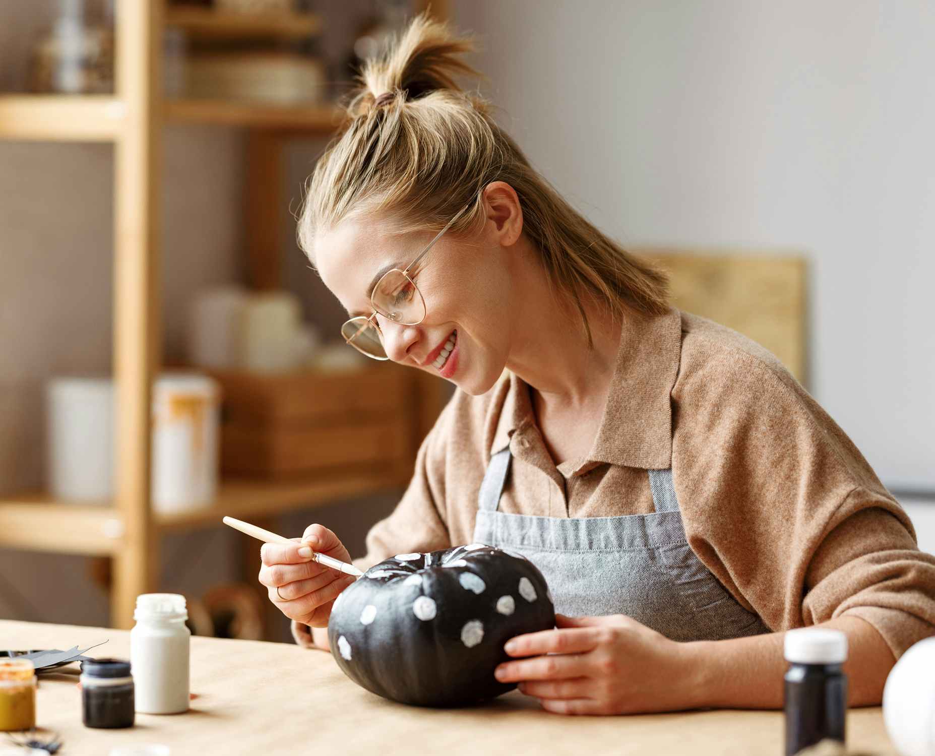woman painting polka dots on black and white pumpkin