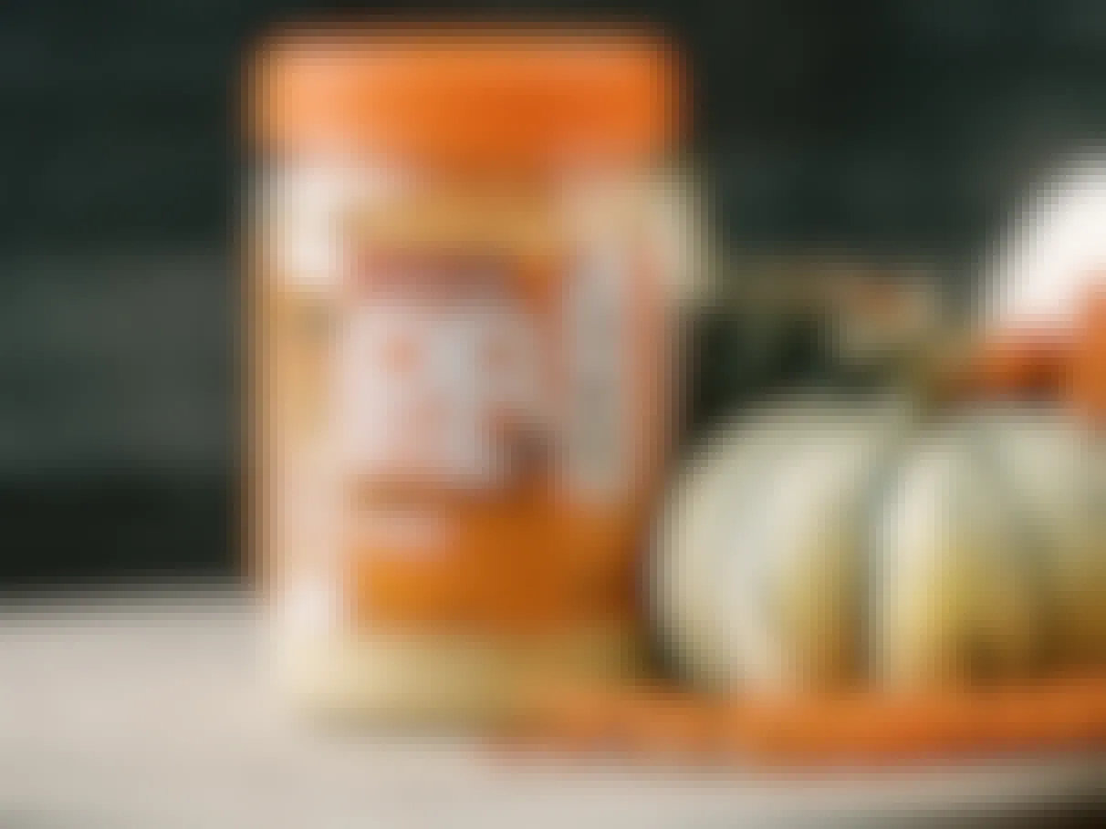 a jar of some pumpkin spice PBfit powder on a counter next to a gourd