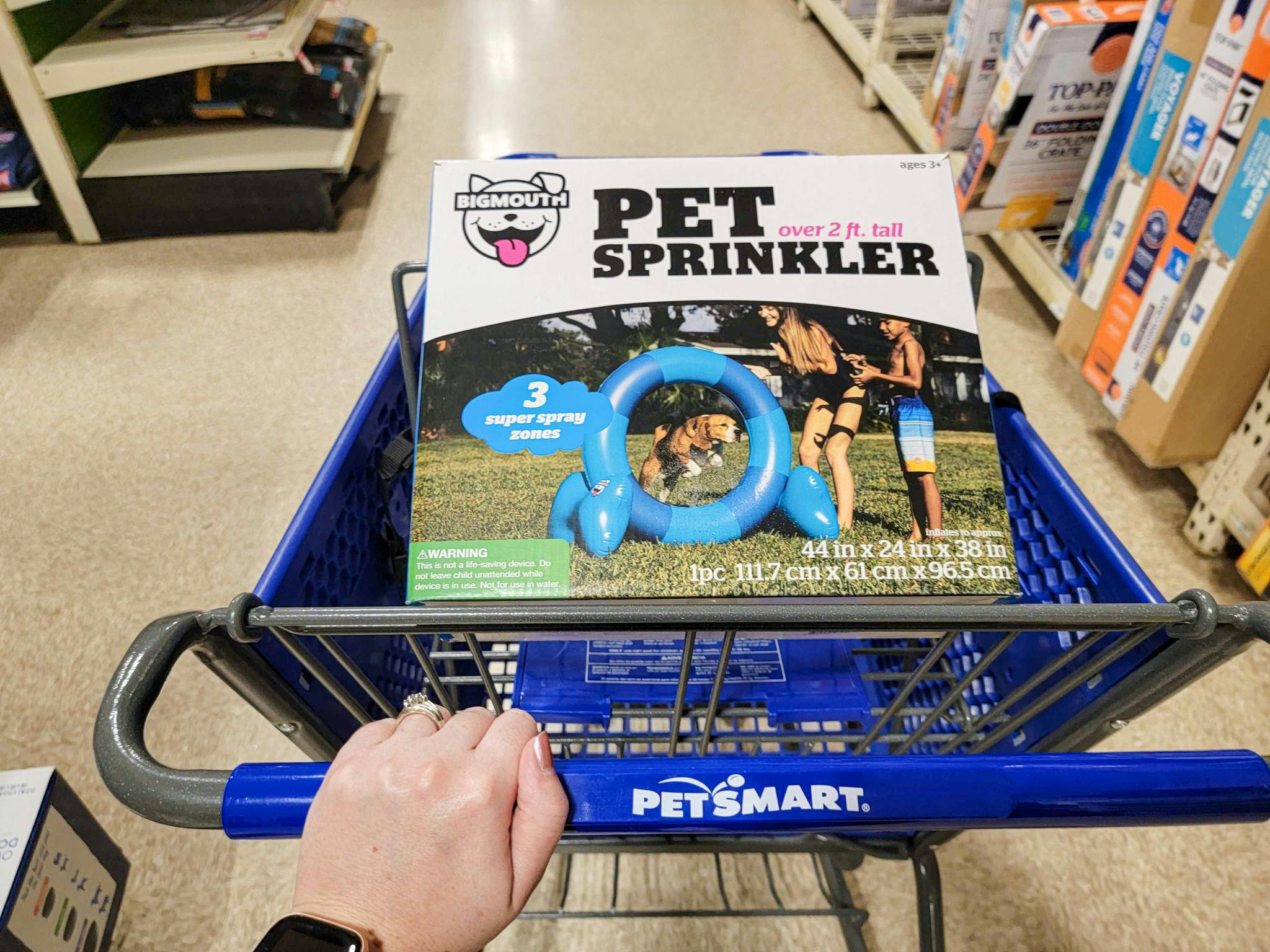 hand pushing a cart with a large pet sprinkler in it