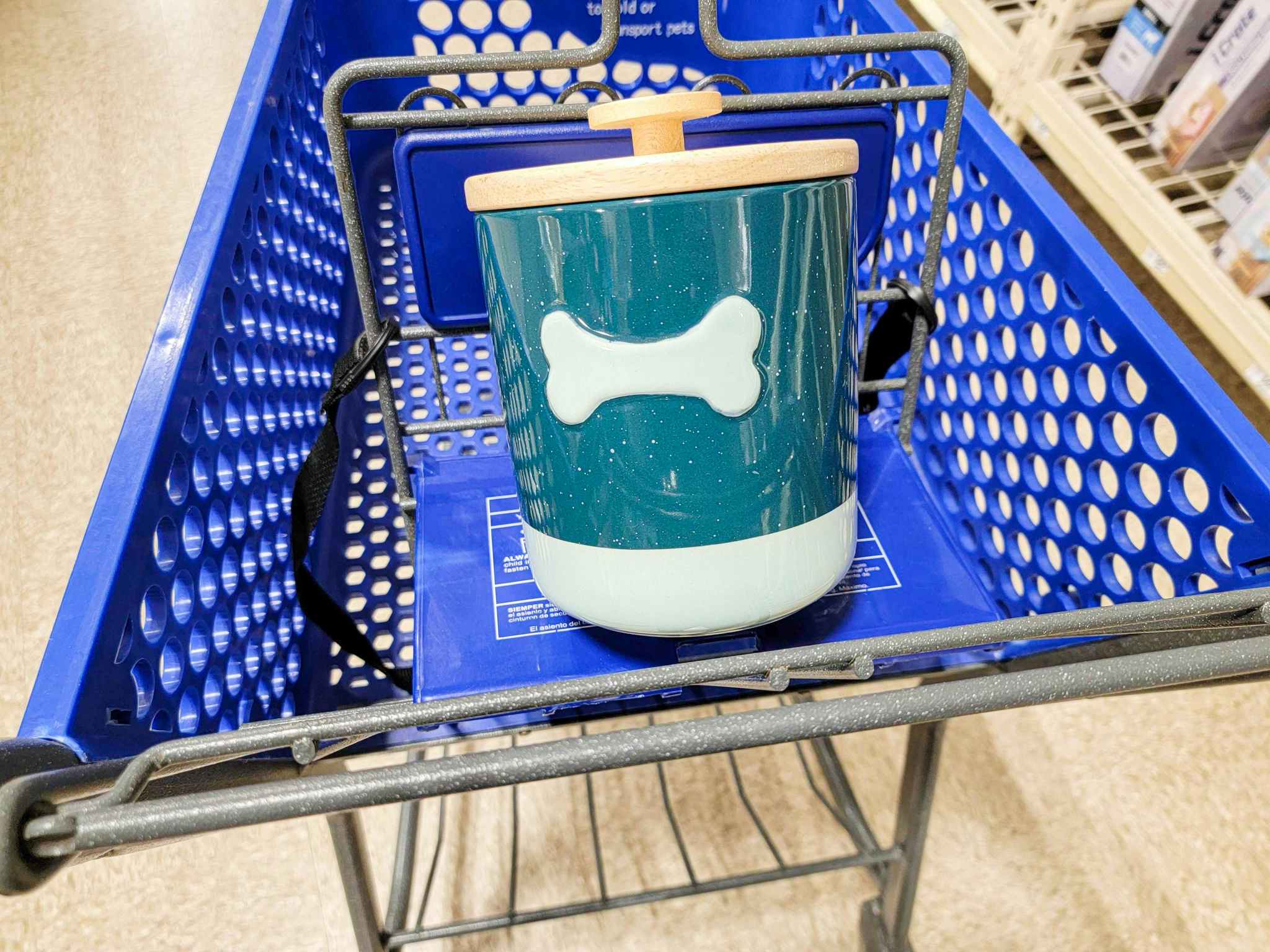 a blue dog treat holder with a teal bone on it in a cart