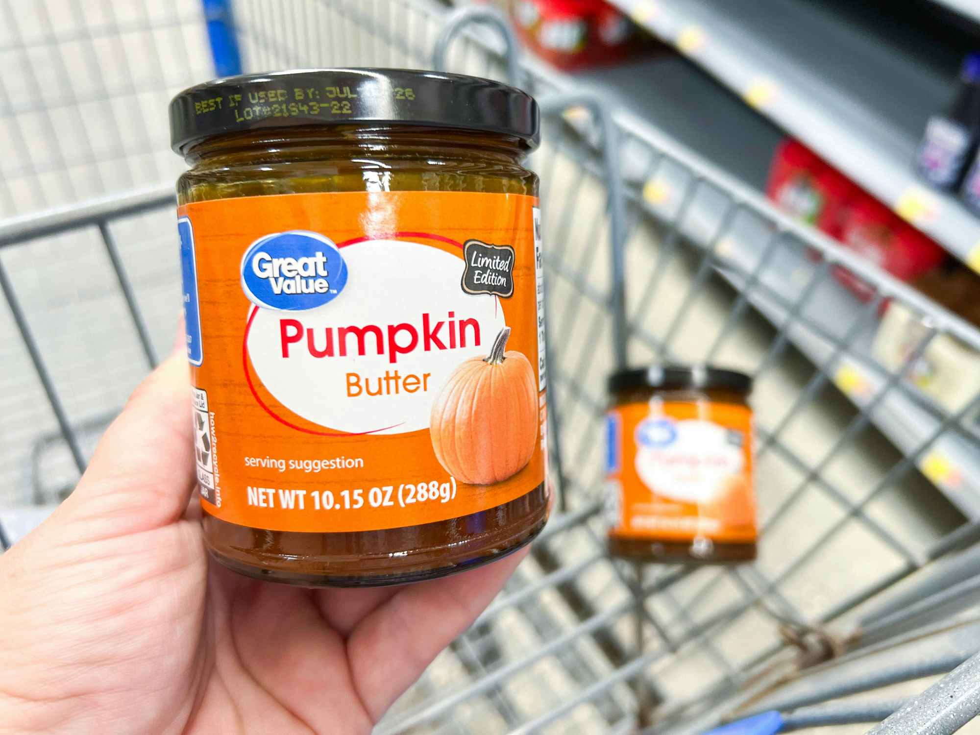 someone holding a jar of Great Value Pumpkin Butter above a cart at Walmart
