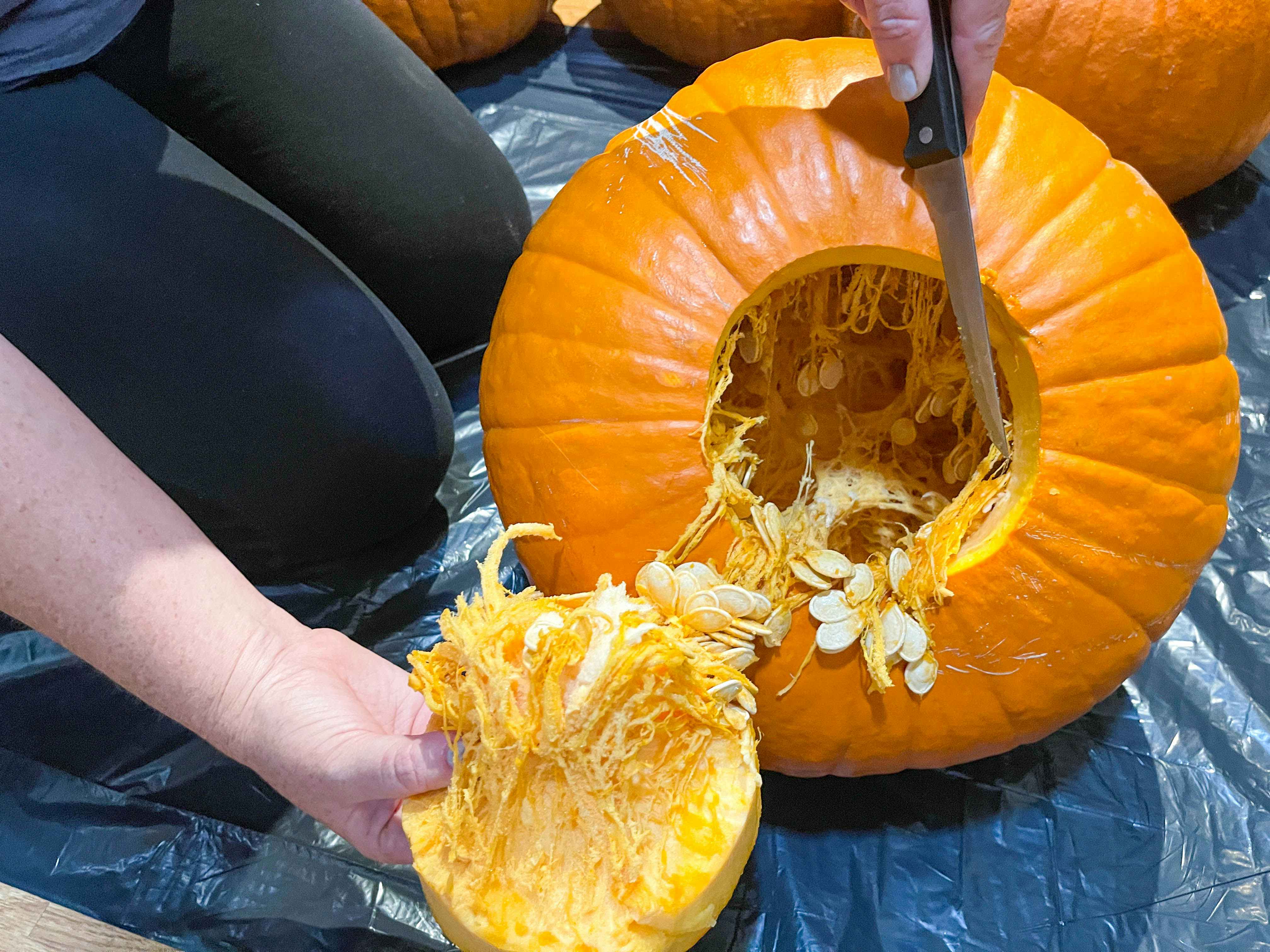 a person pulling the bottom out of a cut pumpkin