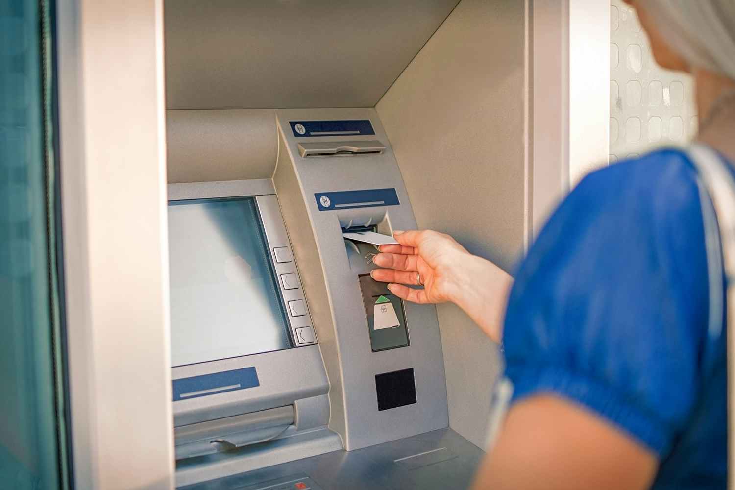 a person putting  a credit card into an atm 