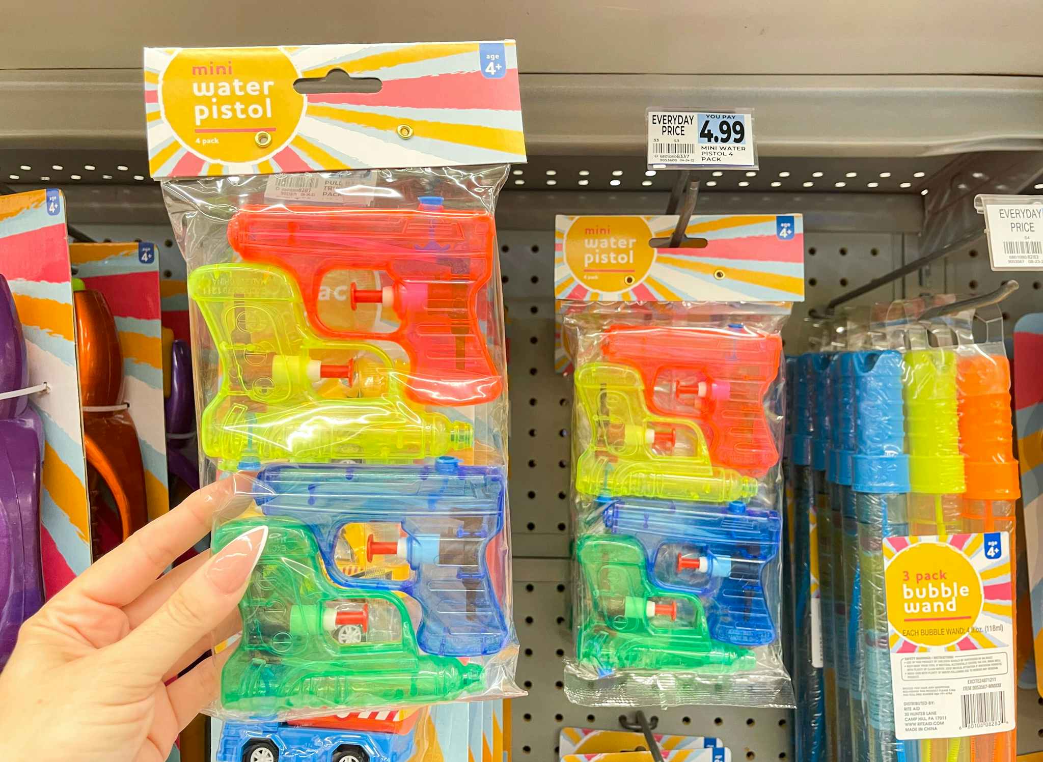 hand holding water pistols next to price tag