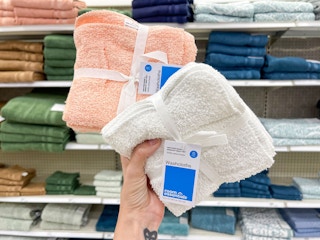hand holding room essentials washcloth sets in from of a target shelf