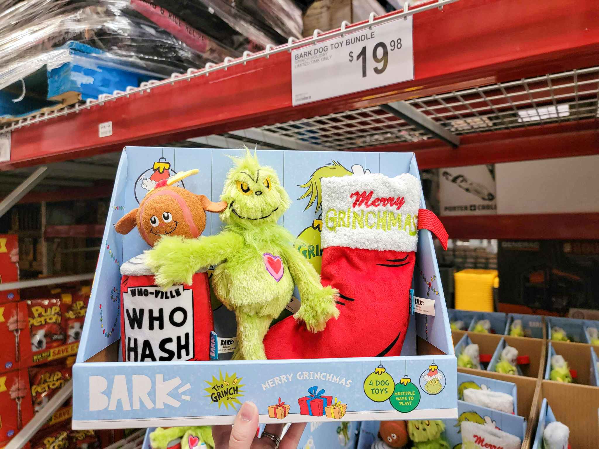 hand holding a 4-pack of grinch dog toys by bark