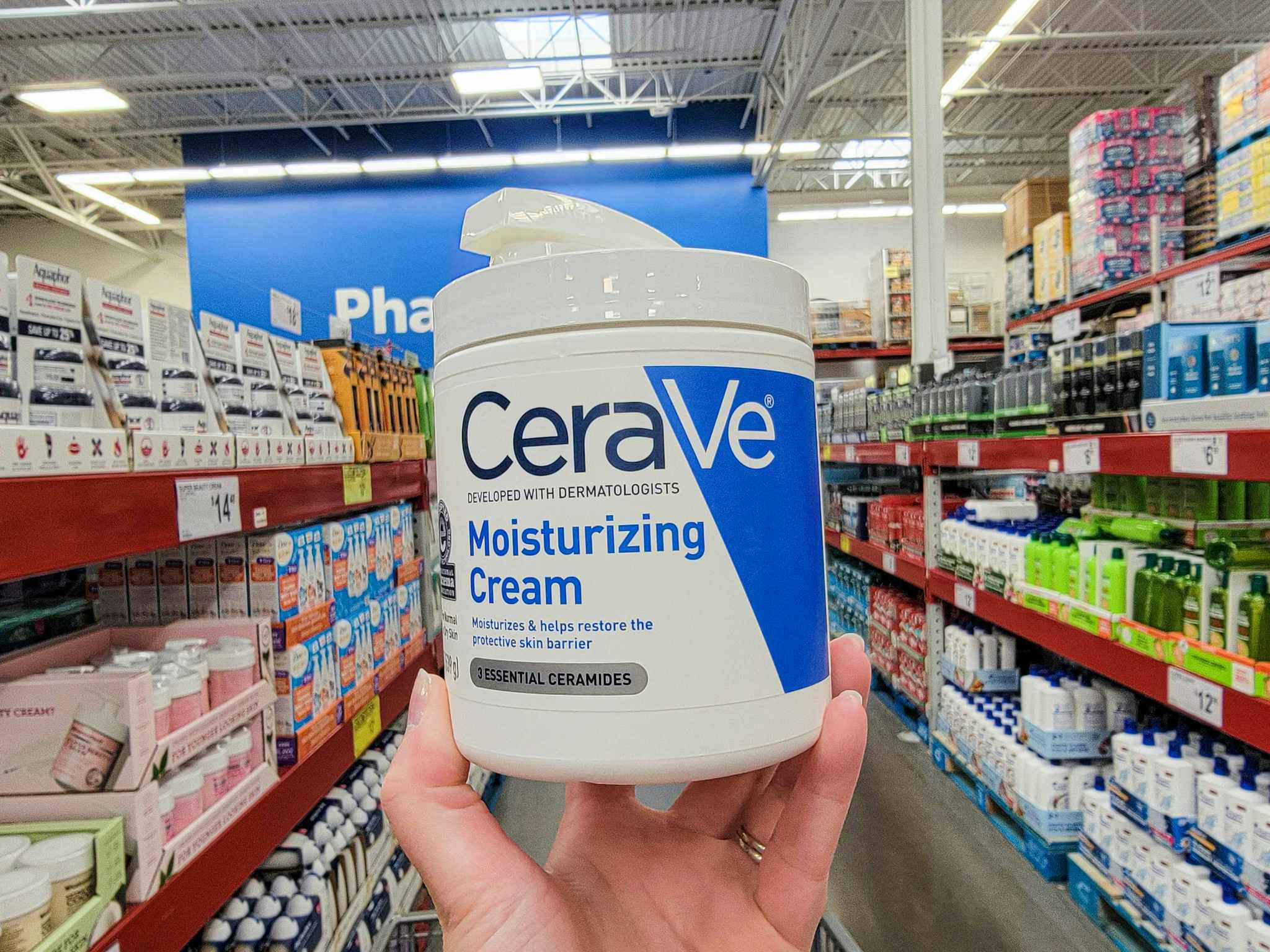 hand holding a large tub of cerave moisturizing cream