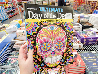 hand holding a day of the dead coloring book