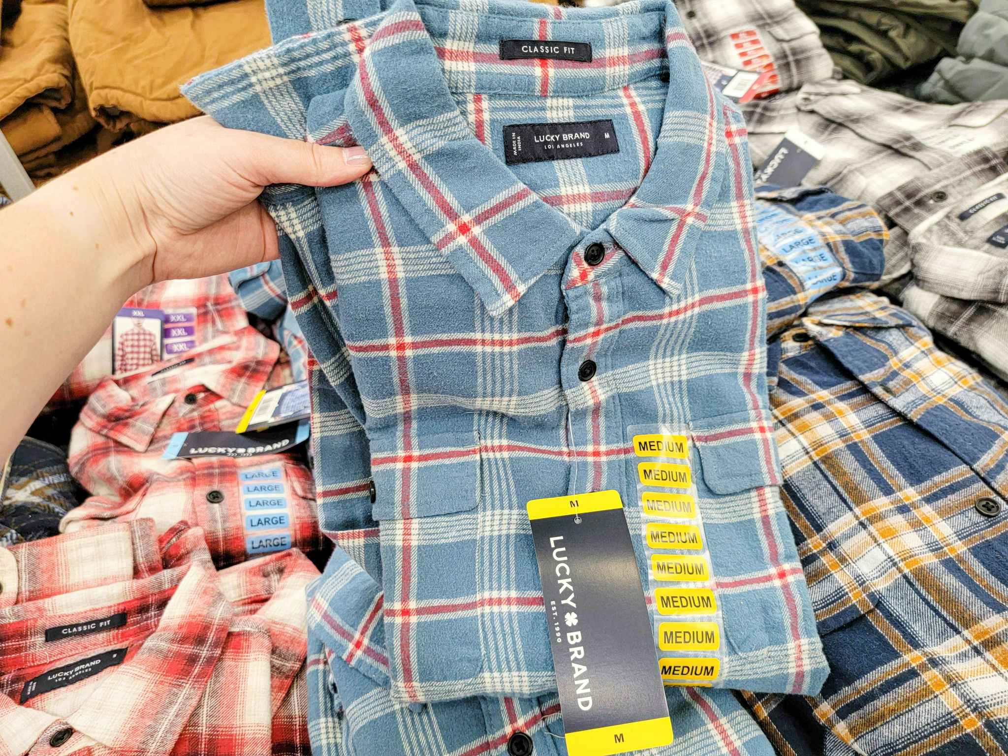 hand holding a blue with red plaid mens lucky brand plaid shirt