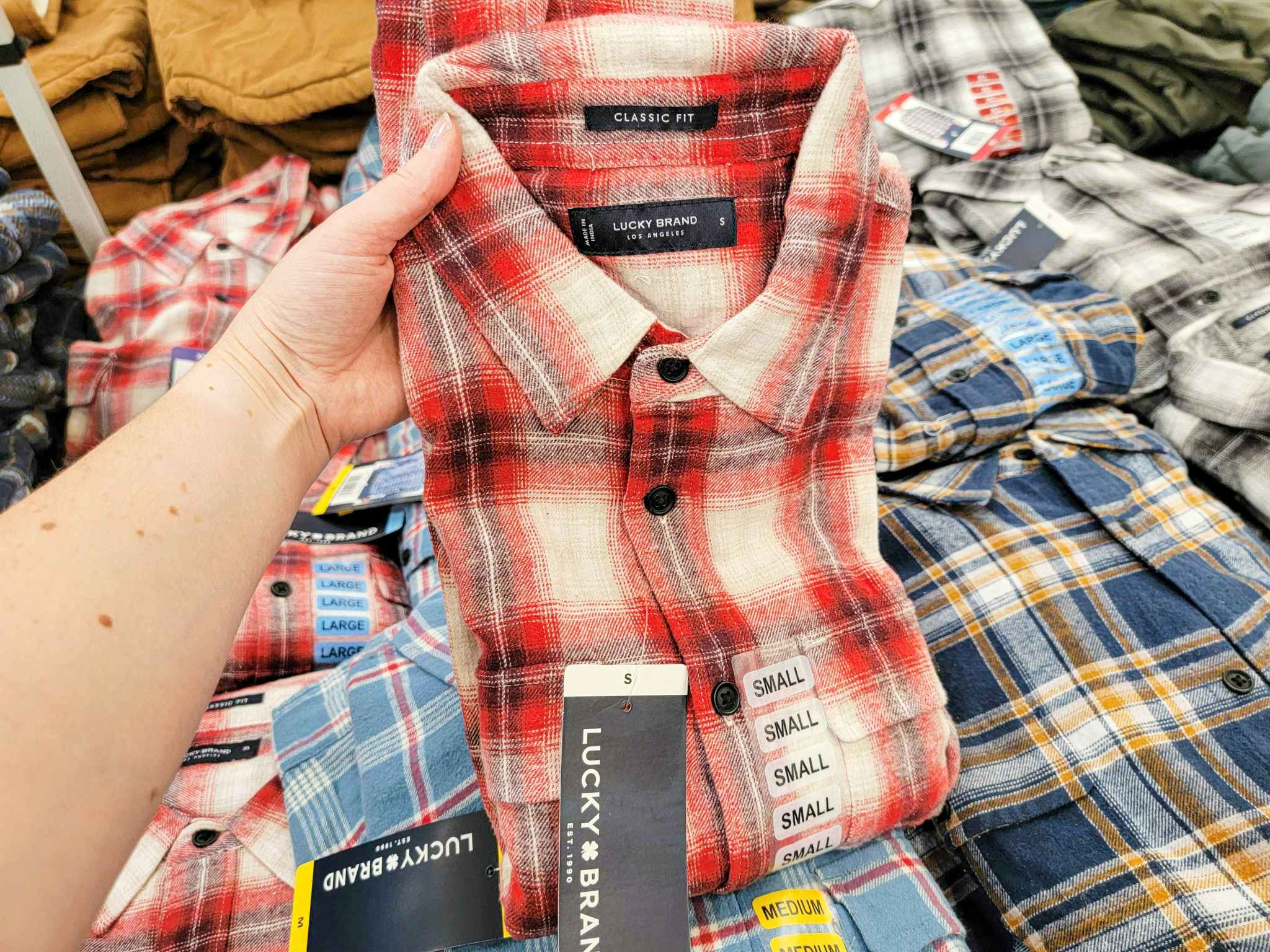 hand holding a red plaid mens lucky brand shirt