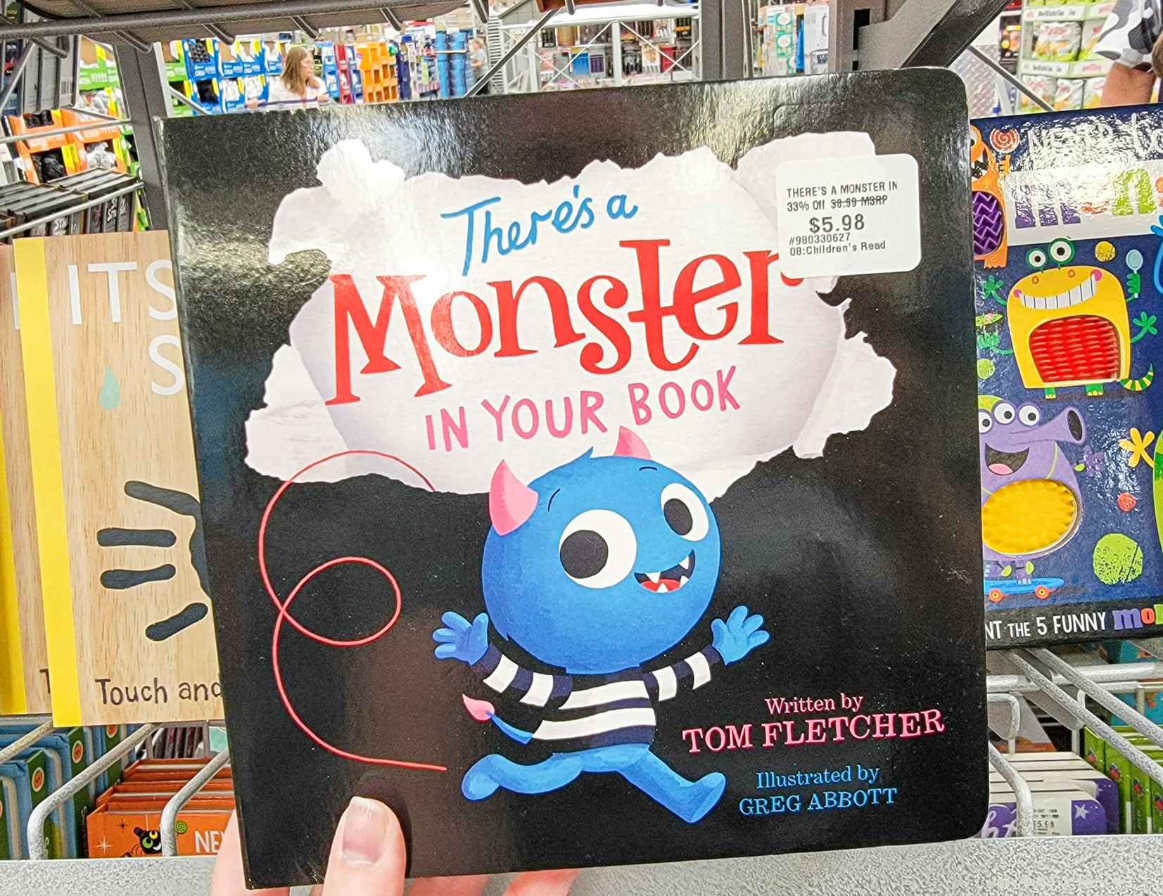 hand holding a kids board book called there's a monster in your book