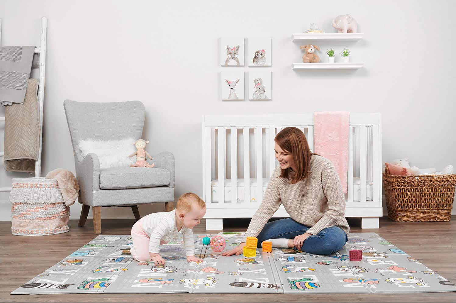 a mother and baby playing on a foam abc playmat