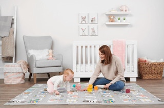 a mother and baby playing on a foam abc playmat
