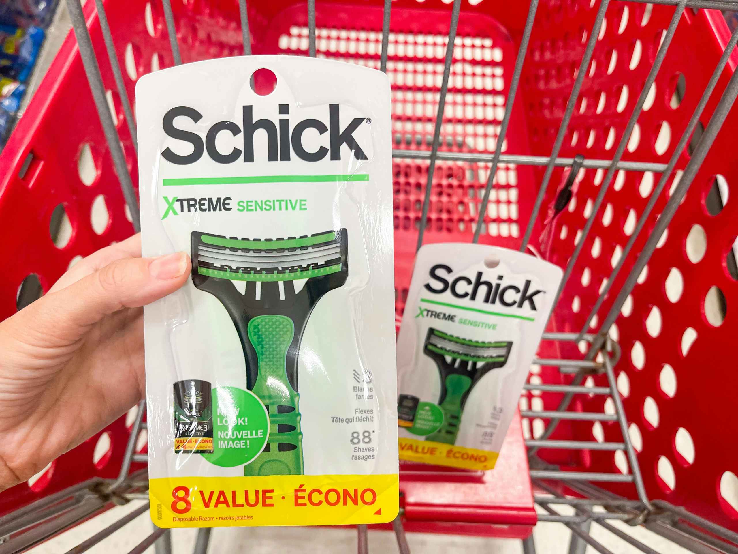 A Schick Xtreme Sensitive razor held out by hand in front of another Schick razor sitting in a cart.