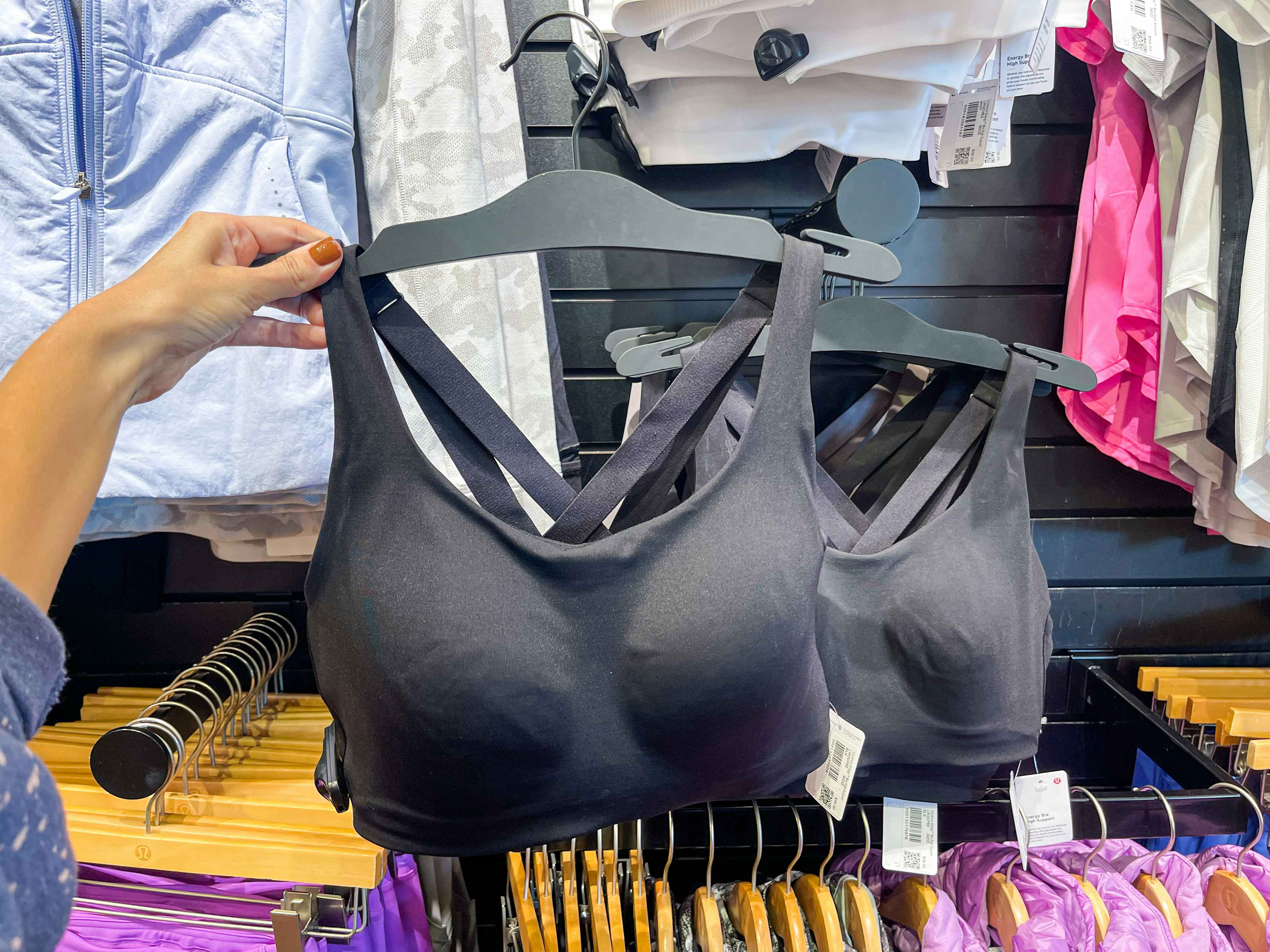 A black sports bra held out by hand in front of other sports bras.