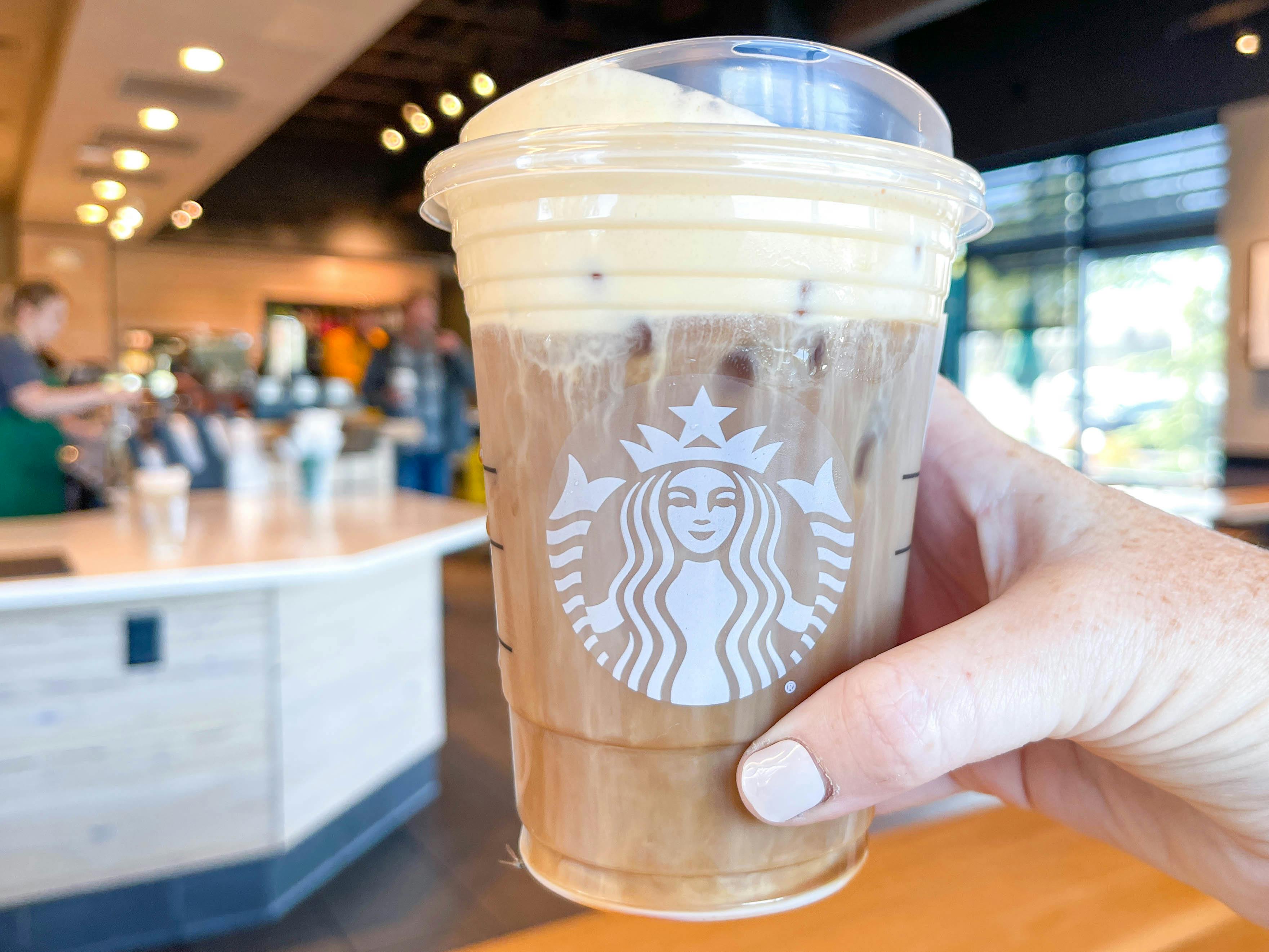 a person grabing a starbucks drink on counter 
