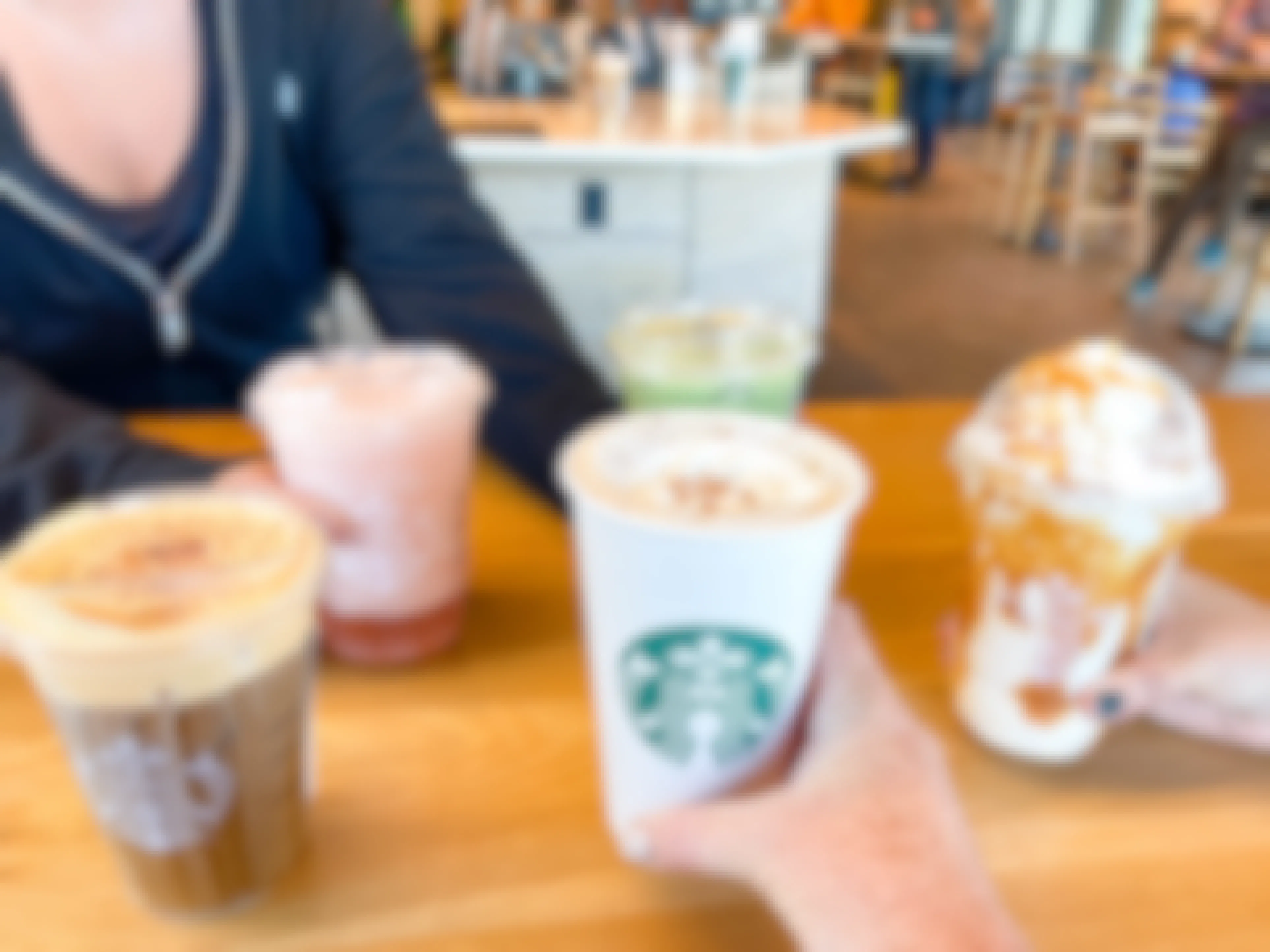 a group of people grabbing a starbucks drink on table