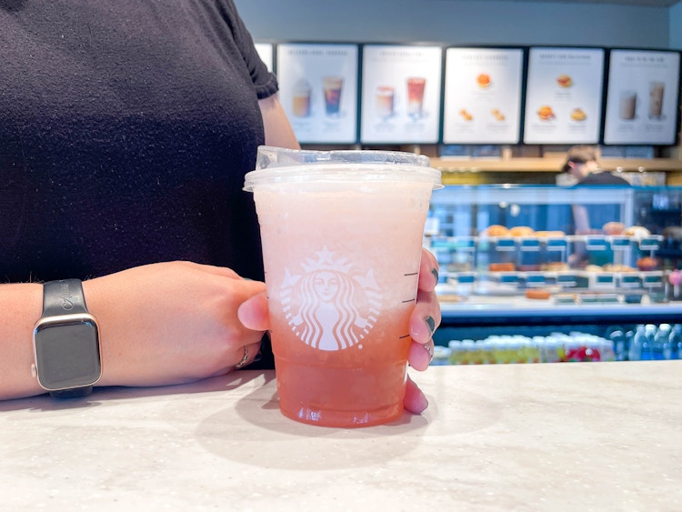 a pink iced starbucks drink being held in starbucks