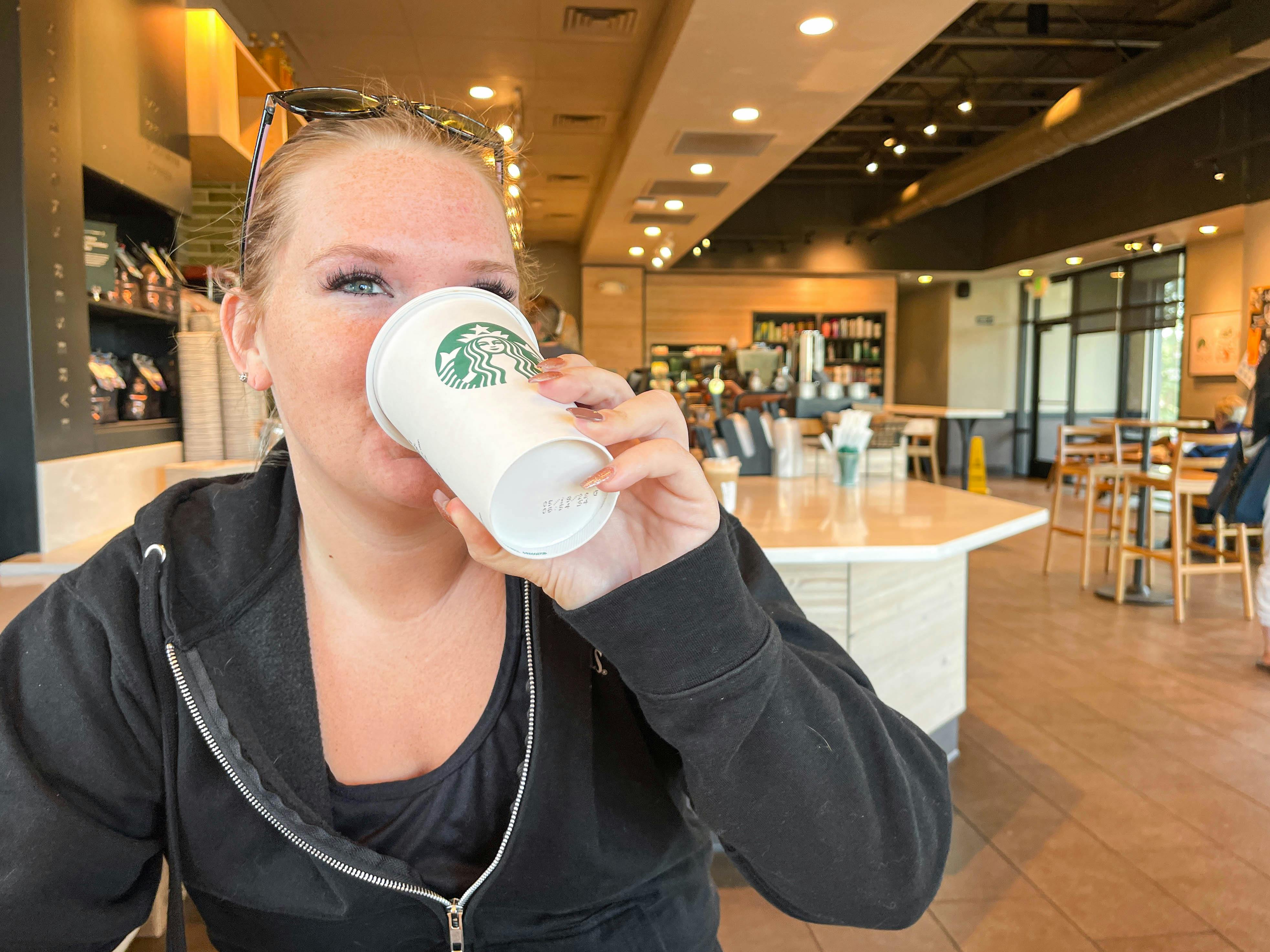 a woman drinking a starbucks drink in starbucks