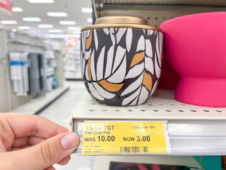 candle on shelf and hand holding clearance tag