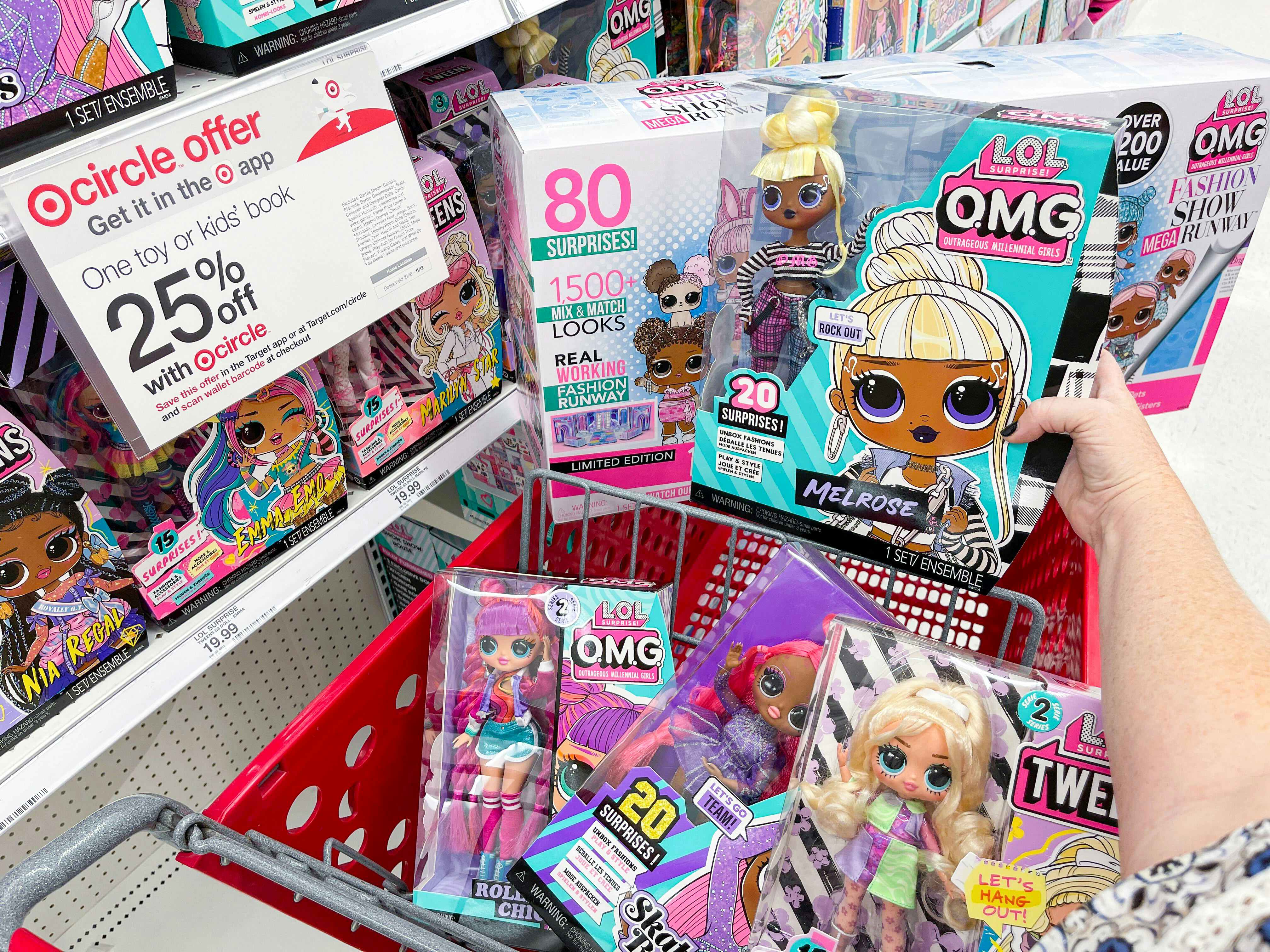 A person holding an LOL Surprise doll over a cart full of more dolls next to a sign for the Target Toy Book sale for 25% off a toy or book.